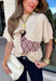 Cozy season just got a whole lot cuter with this playful dachshund dog sweater from New In. A tan and brown pup wraps around the neutral knit wearing its very own pink, tan, and black argyle sweater for a fun design that’s guaranteed to get compliments. The short sleeves make it perfect for those in-between fall days, while the ribbed mock neckline gives it an extra cozy touch. 