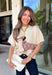 Cozy season just got a whole lot cuter with this playful dachshund dog sweater from New In. A tan and brown pup wraps around the neutral knit wearing its very own pink, tan, and black argyle sweater for a fun design that’s guaranteed to get compliments. The short sleeves make it perfect for those in-between fall days, while the ribbed mock neckline gives it an extra cozy touch. 