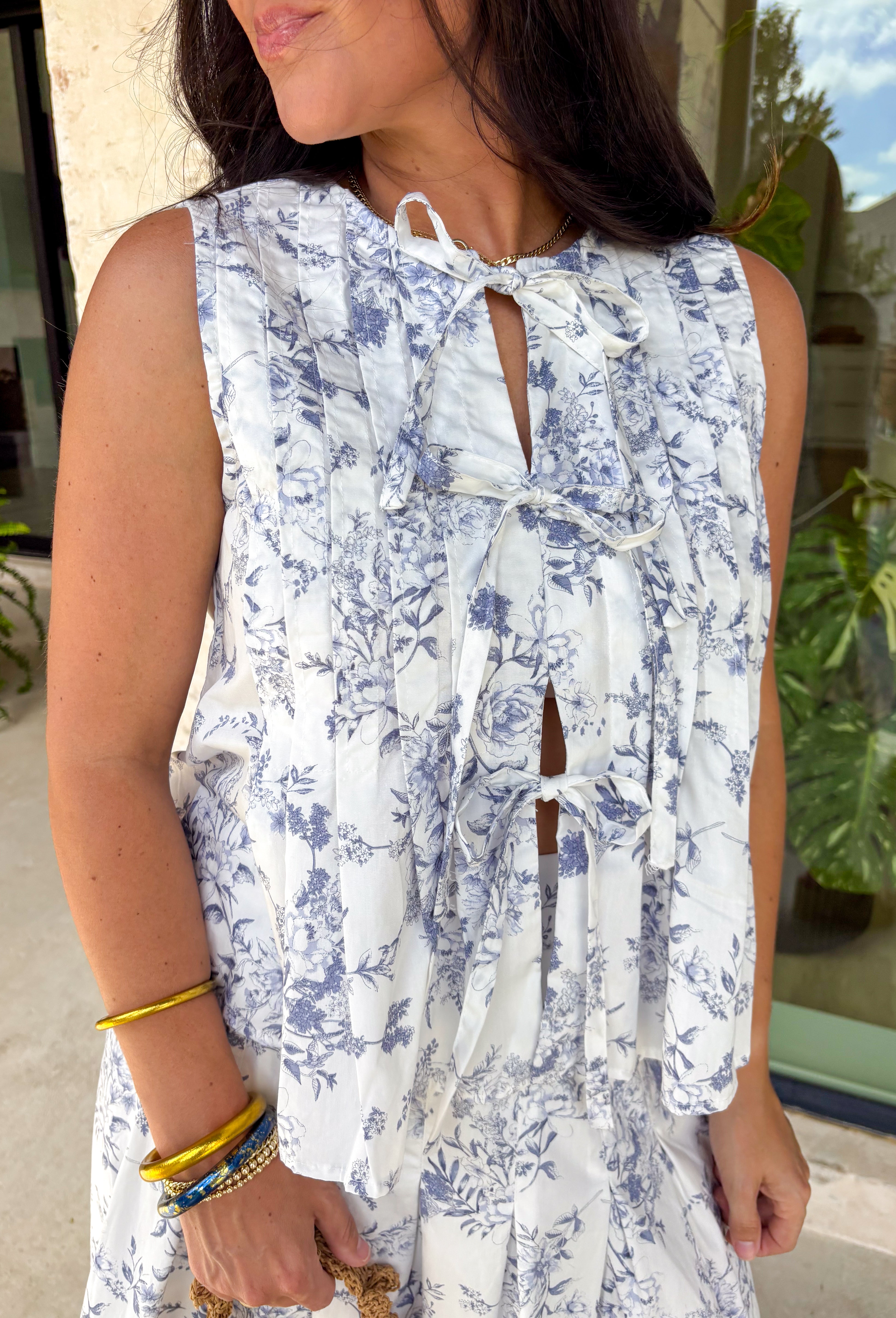 Crisp white and navy is always a yes! This sleeveless top features a timeless navy floral print throughout for a fresh, polished look that’s perfect for warm days. The three tie details along the top add a playful, feminine touch, while the soft pleating along the front gives it beautiful shape and movement. Lightweight in 100% cotton and easy to style, this top is perfect for everything from weekend brunch to vacation dinners.