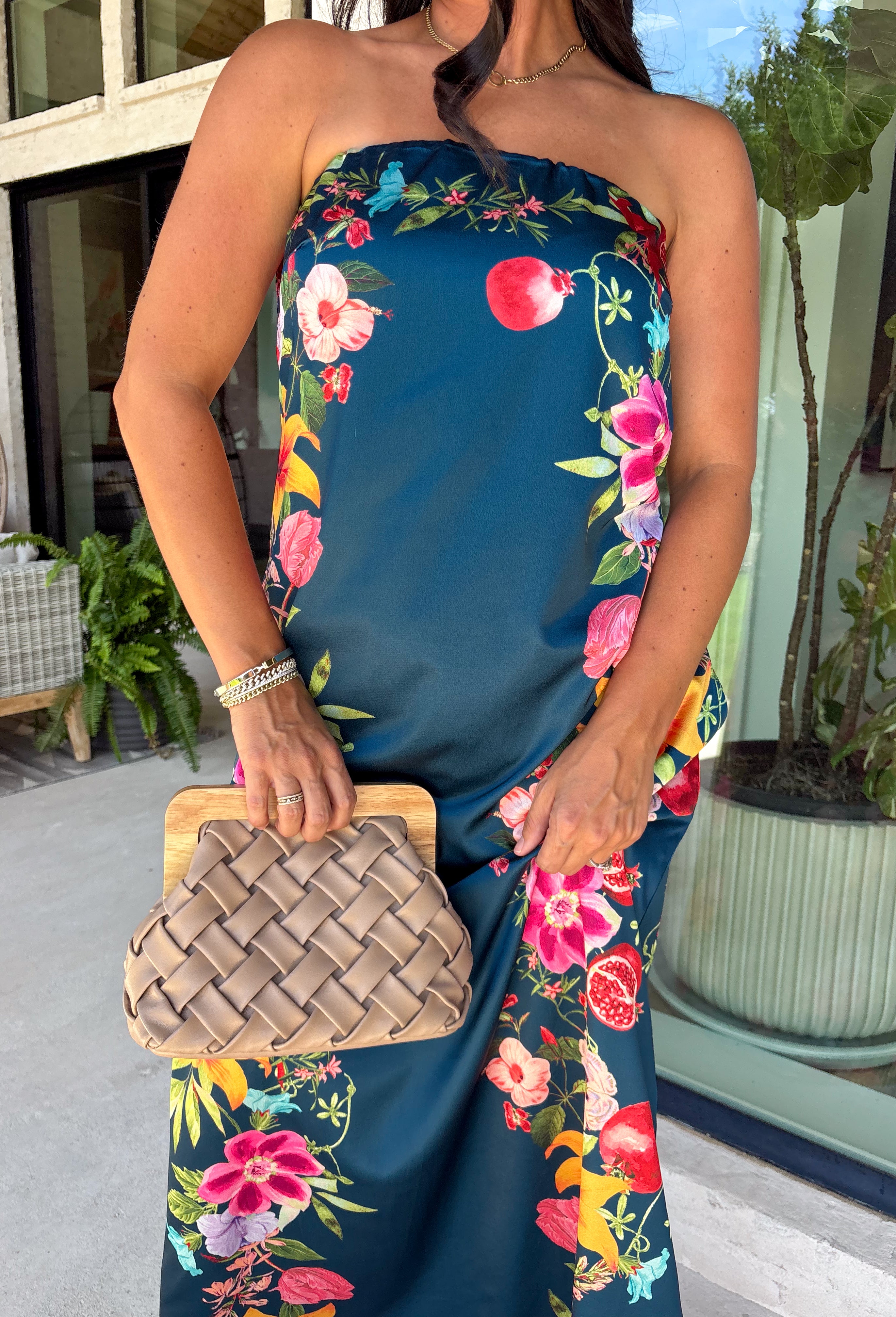 Make an unforgettable entrance in this stunning satin midi dress! The rich dark teal color creates the perfect backdrop for the vibrant floral print that blooms along each side in shades of pink, purple, green, yellow, red, and blue. The strapless neckline gives it an effortlessly elegant feel, while the smooth satin fabric adds a beautiful touch of shine. 