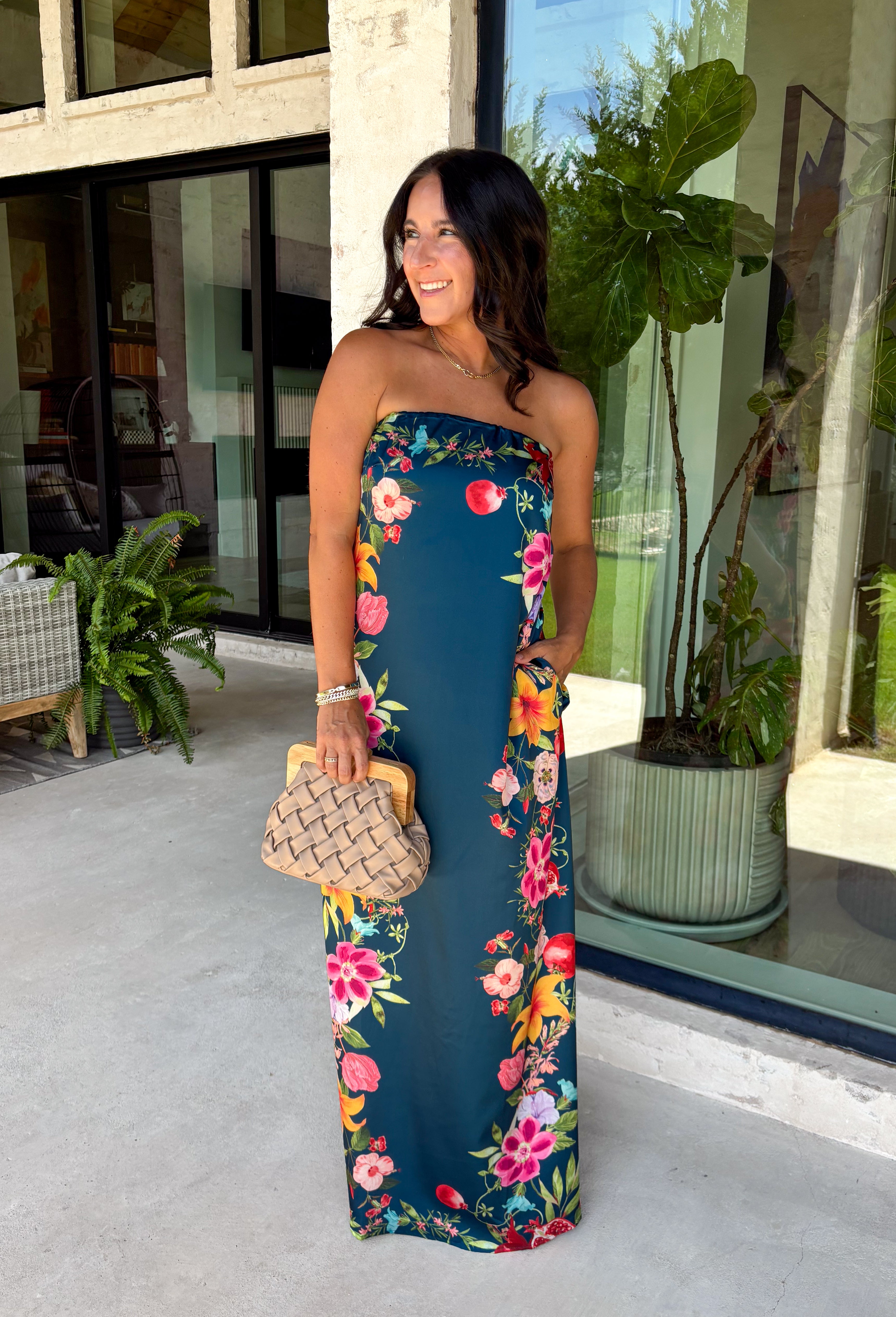 Make an unforgettable entrance in this stunning satin midi dress! The rich dark teal color creates the perfect backdrop for the vibrant floral print that blooms along each side in shades of pink, purple, green, yellow, red, and blue. The strapless neckline gives it an effortlessly elegant feel, while the smooth satin fabric adds a beautiful touch of shine. 