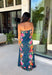 Make an unforgettable entrance in this stunning satin midi dress! The rich dark teal color creates the perfect backdrop for the vibrant floral print that blooms along each side in shades of pink, purple, green, yellow, red, and blue. The strapless neckline gives it an effortlessly elegant feel, while the smooth satin fabric adds a beautiful touch of shine. 