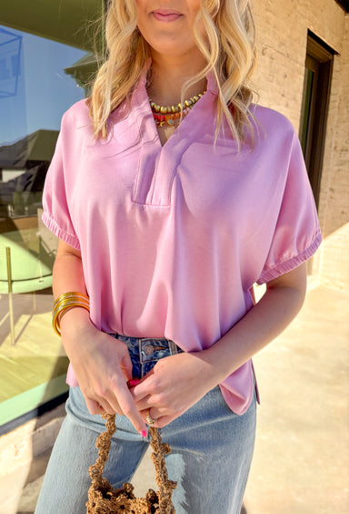 Simple, soft, and effortlessly polished, this baby pink short sleeve top by Entro is an easy spring staple you’ll wear on repeat. Designed with a split v-neck and clean collar band, it has a relaxed look that still feels put together. Elasticated sleeve openings add comfort, while the back yoke with pleat detail gives it a flattering drape. Lightweight and soft to the touch, this top is perfect for everyday wear as the weather warms up.