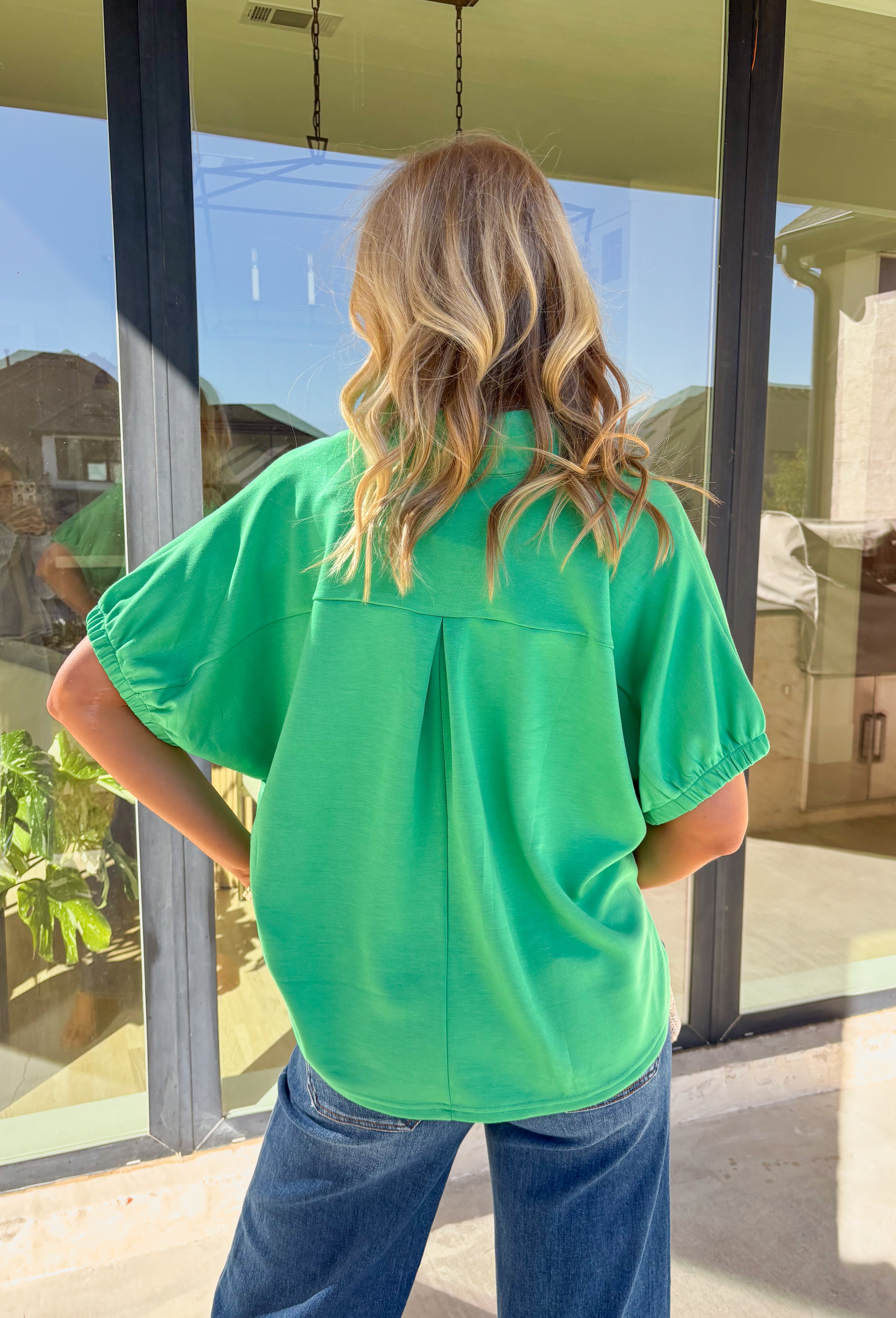 Simple, soft, and effortlessly polished, this green short sleeve top by Entro is an easy spring staple you’ll wear on repeat. Designed with a split v-neck and clean collar band, it has a relaxed look that still feels put together. Elasticated sleeve openings add comfort, while the back yoke with pleat detail gives it a flattering drape. Lightweight and soft to the touch, this top is perfect for everyday wear as the weather warms up.