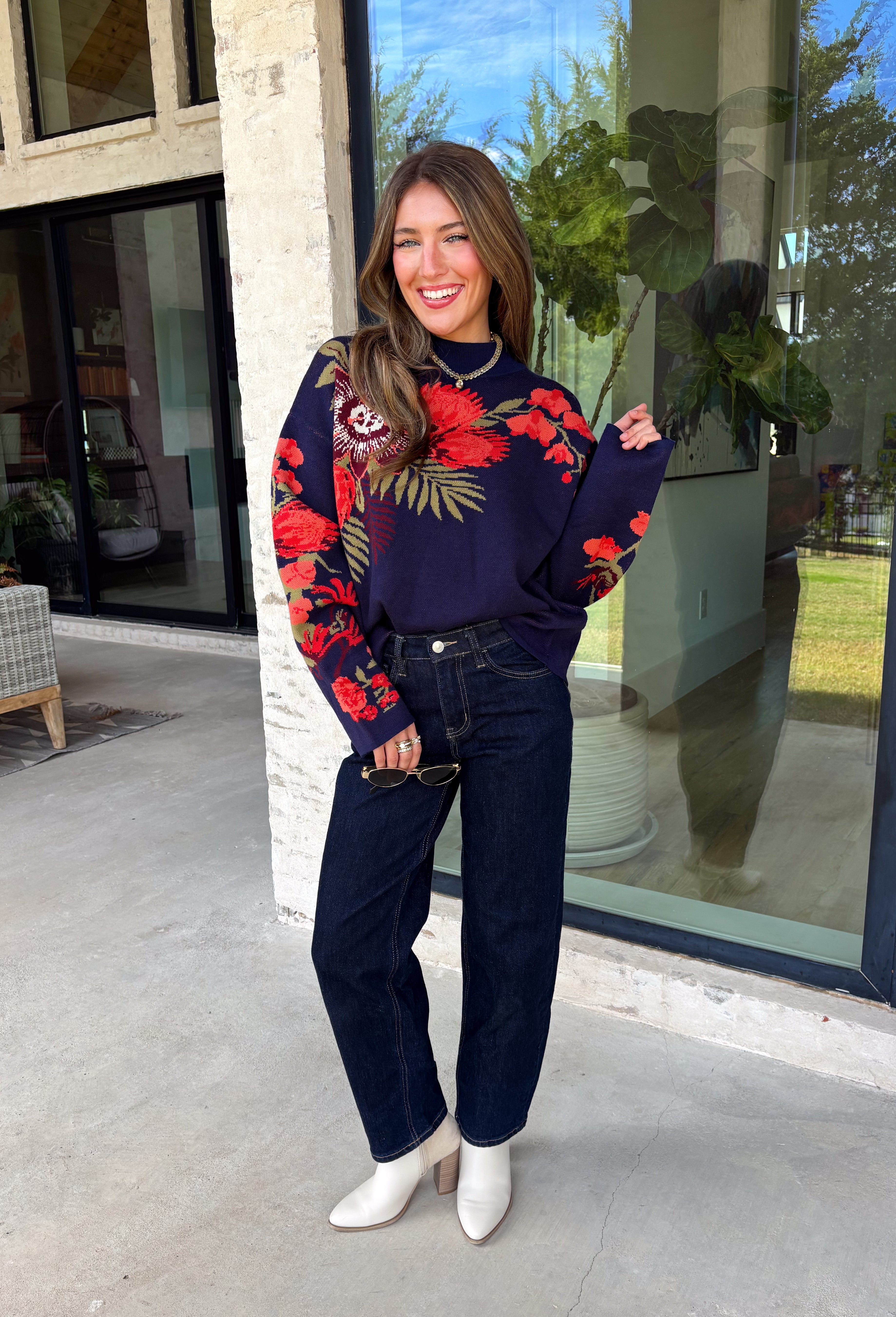 Wrap yourself in cozy comfort with a sweater that's bursting with beautiful seasonal color! This navy knit sweater is adorned with a vibrant floral motif featuring shades of coral, burgundy, olive green, and off white, creating the perfect blend of timeless charm and autumn style. The mock neckline and relaxed drop shoulders give it an effortlessly cozy feel, while the soft knit fabric makes it an easy choice for crisp mornings, weekend outings, and everything in between. 
