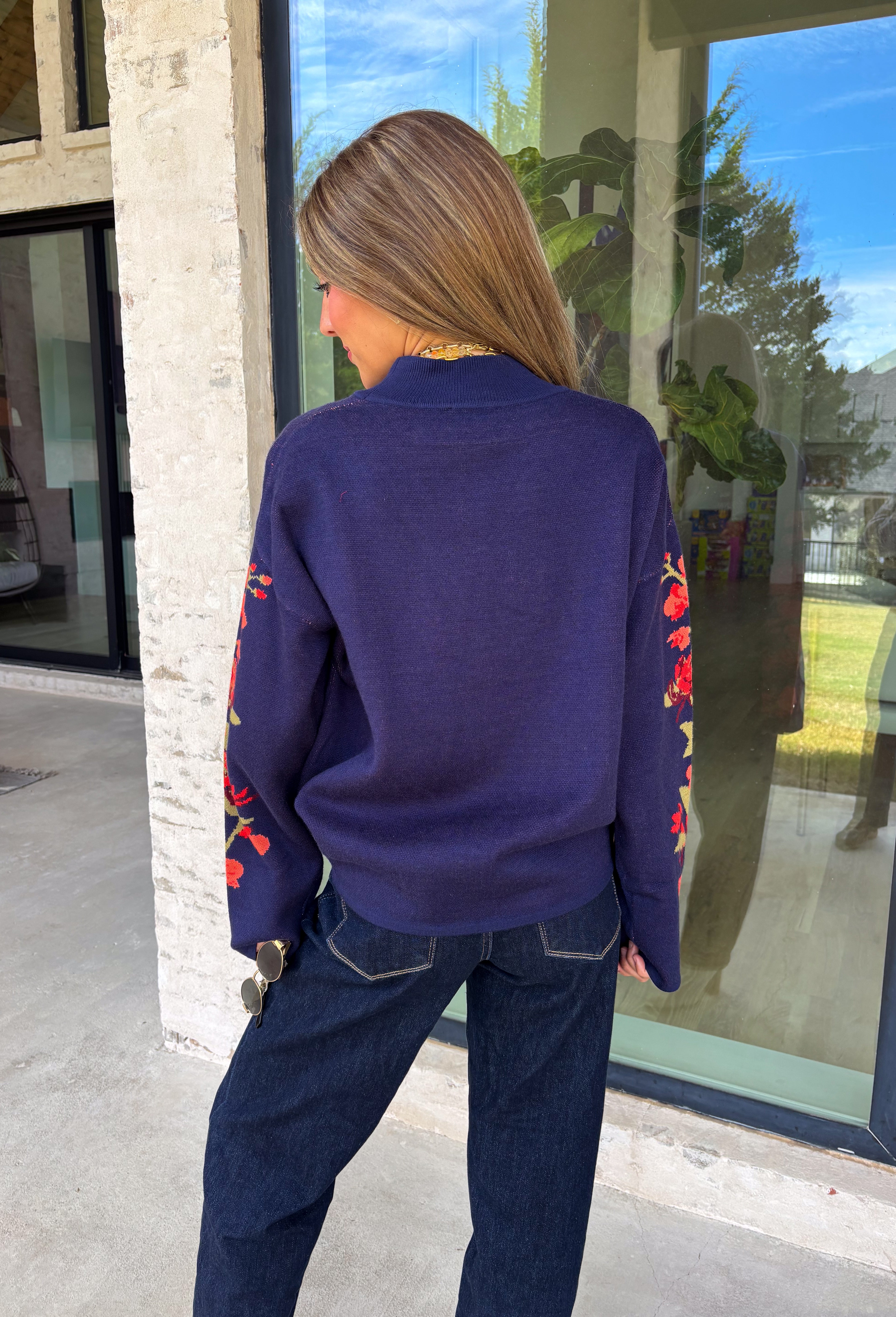 Wrap yourself in cozy comfort with a sweater that's bursting with beautiful seasonal color! This navy knit sweater is adorned with a vibrant floral motif featuring shades of coral, burgundy, olive green, and off white, creating the perfect blend of timeless charm and autumn style. The mock neckline and relaxed drop shoulders give it an effortlessly cozy feel, while the soft knit fabric makes it an easy choice for crisp mornings, weekend outings, and everything in between. 
