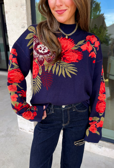 Wrap yourself in cozy comfort with a sweater that's bursting with beautiful seasonal color! This navy knit sweater is adorned with a vibrant floral motif featuring shades of coral, burgundy, olive green, and off white, creating the perfect blend of timeless charm and autumn style. The mock neckline and relaxed drop shoulders give it an effortlessly cozy feel, while the soft knit fabric makes it an easy choice for crisp mornings, weekend outings, and everything in between. 