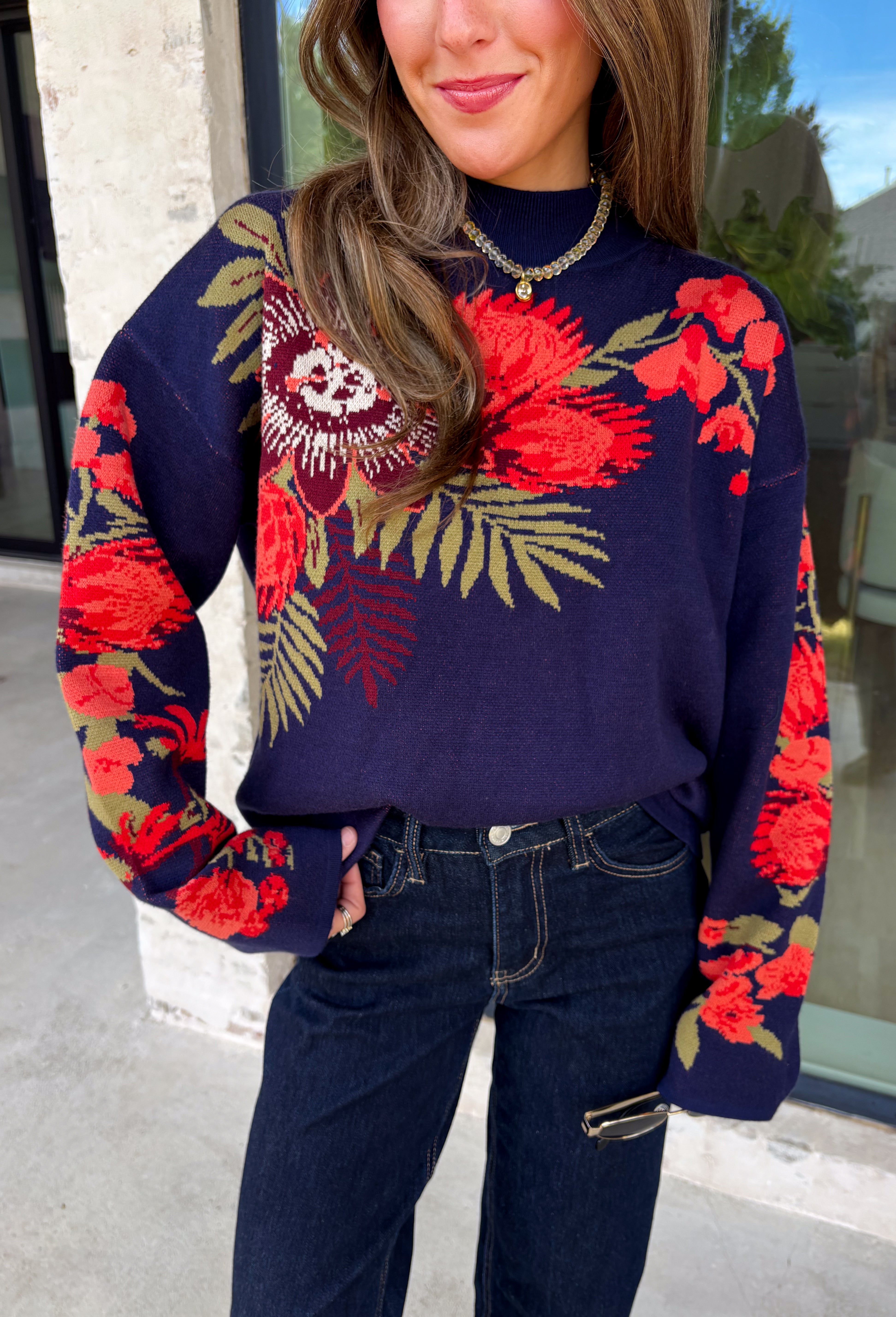 Wrap yourself in cozy comfort with a sweater that's bursting with beautiful seasonal color! This navy knit sweater is adorned with a vibrant floral motif featuring shades of coral, burgundy, olive green, and off white, creating the perfect blend of timeless charm and autumn style. The mock neckline and relaxed drop shoulders give it an effortlessly cozy feel, while the soft knit fabric makes it an easy choice for crisp mornings, weekend outings, and everything in between. 