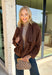 Elevate your layering game with this effortlessly chic faux suede jacket from Entro. Designed in a rich brown hue, this open-front jacket features a beautifully draped lapel that creates an elegant, flattering silhouette. The soft faux suede texture gives it a luxurious feel, while the comfortable stretch fabric makes it easy to wear from morning to night. Whether layered over dresses, blouses, or your favorite sweater, this timeless jacket is the perfect finishing touch for all your fall outfits.