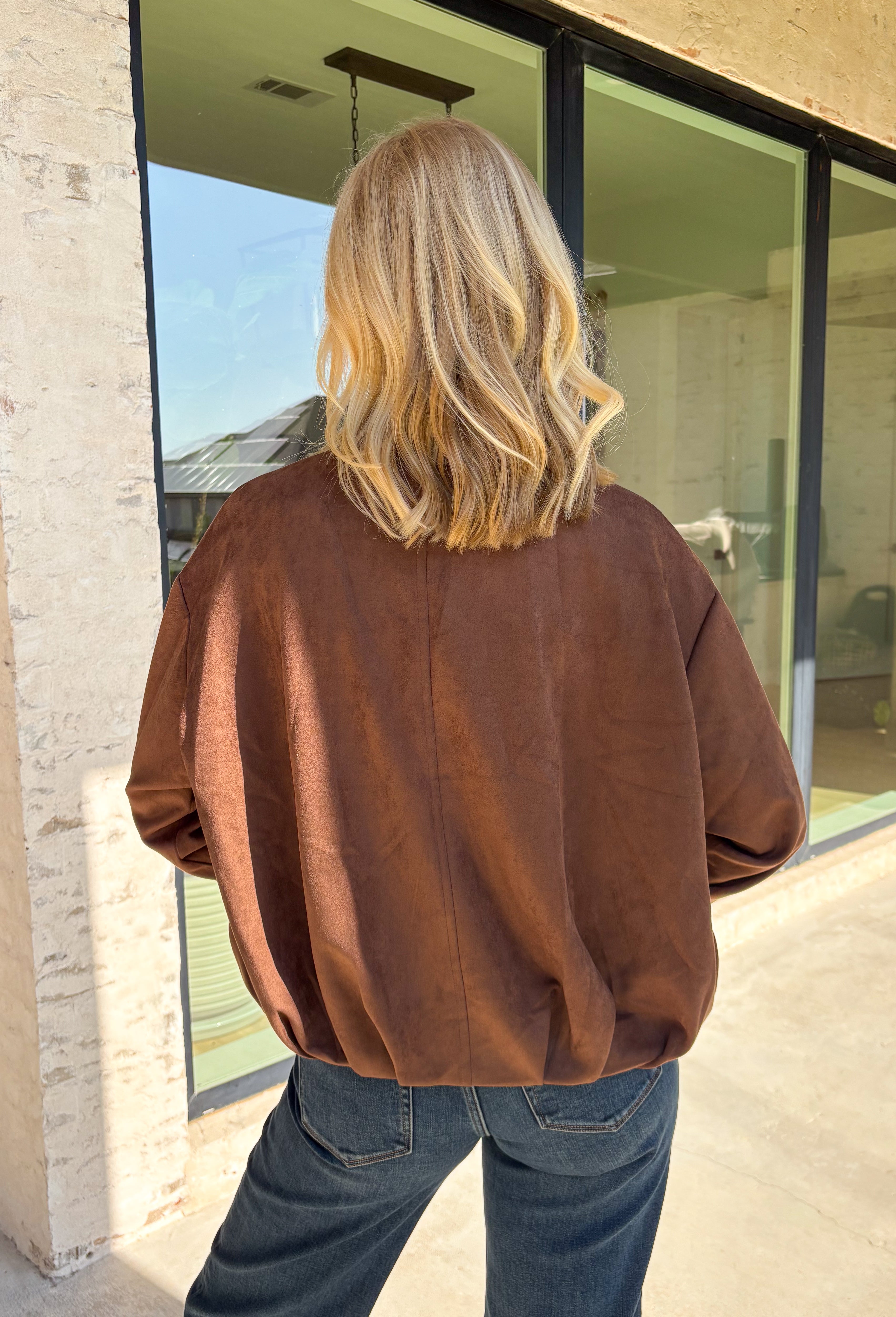 Elevate your layering game with this effortlessly chic faux suede jacket from Entro. Designed in a rich brown hue, this open-front jacket features a beautifully draped lapel that creates an elegant, flattering silhouette. The soft faux suede texture gives it a luxurious feel, while the comfortable stretch fabric makes it easy to wear from morning to night. Whether layered over dresses, blouses, or your favorite sweater, this timeless jacket is the perfect finishing touch for all your fall outfits.