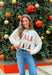 Add a playful pop of holiday cheer to your winter wardrobe with this cozy off-white sweater by Main Strip! Featuring “Fa La La La” embroidered across the front in colorful letters—each with its own fun print—this soft knit is full of festive spirit. Perfect for holiday parties, casual days, or cozy nights in, it’s the kind of merry piece you’ll wear all season long.