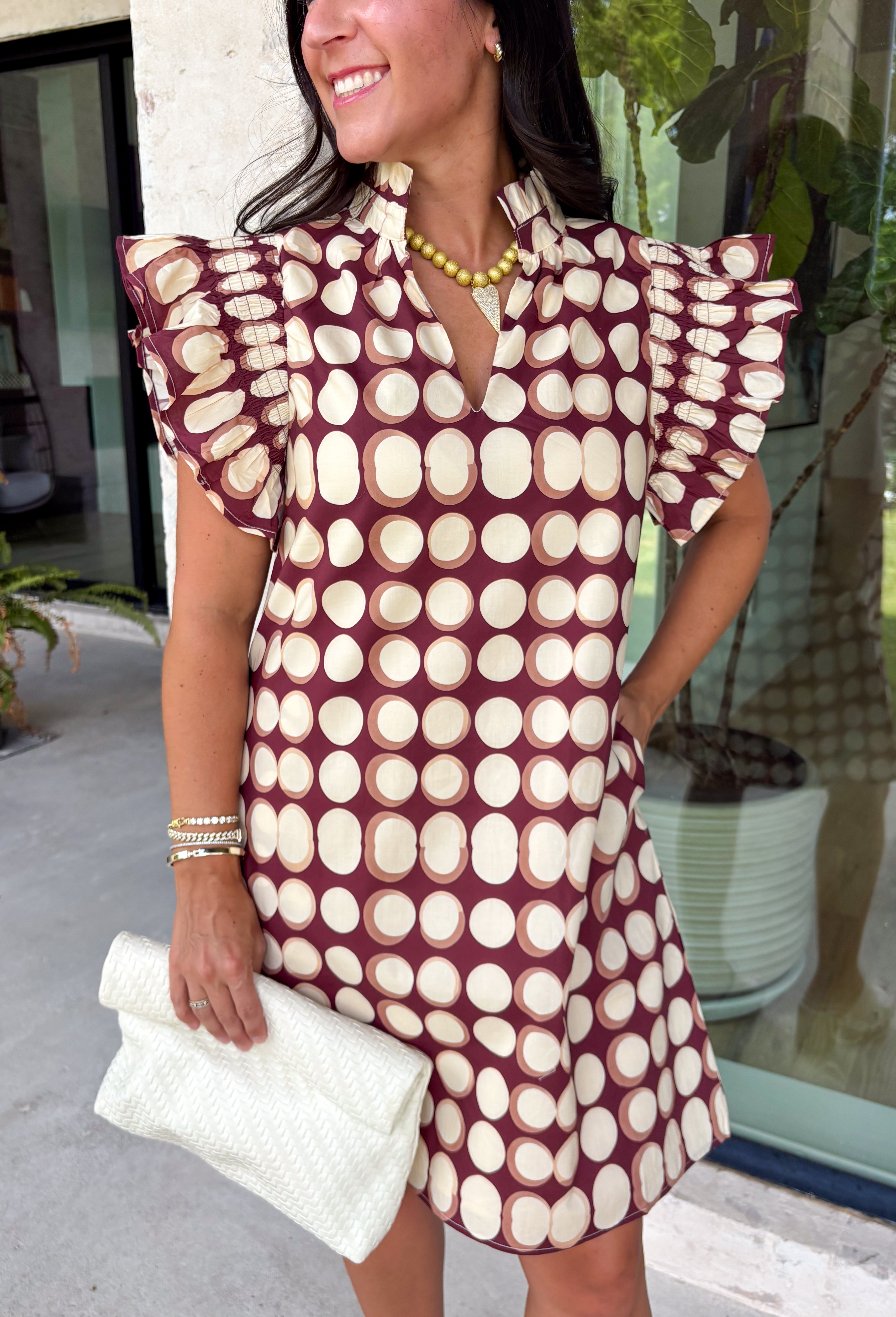 Bring playful charm to your fall wardrobe with this beautiful dress from THML. Designed in a rich burgundy hue with a bold neutral polka dot print, this timeless piece is perfect for everything from brunch dates to seasonal celebrations. The ruffle sleeves are finished with delicate smocking for an extra feminine touch, while the fully lined silhouette offers all-day comfort. Complete with convenient side pockets, this cotton dress is one you'll love reaching for throughout the season.