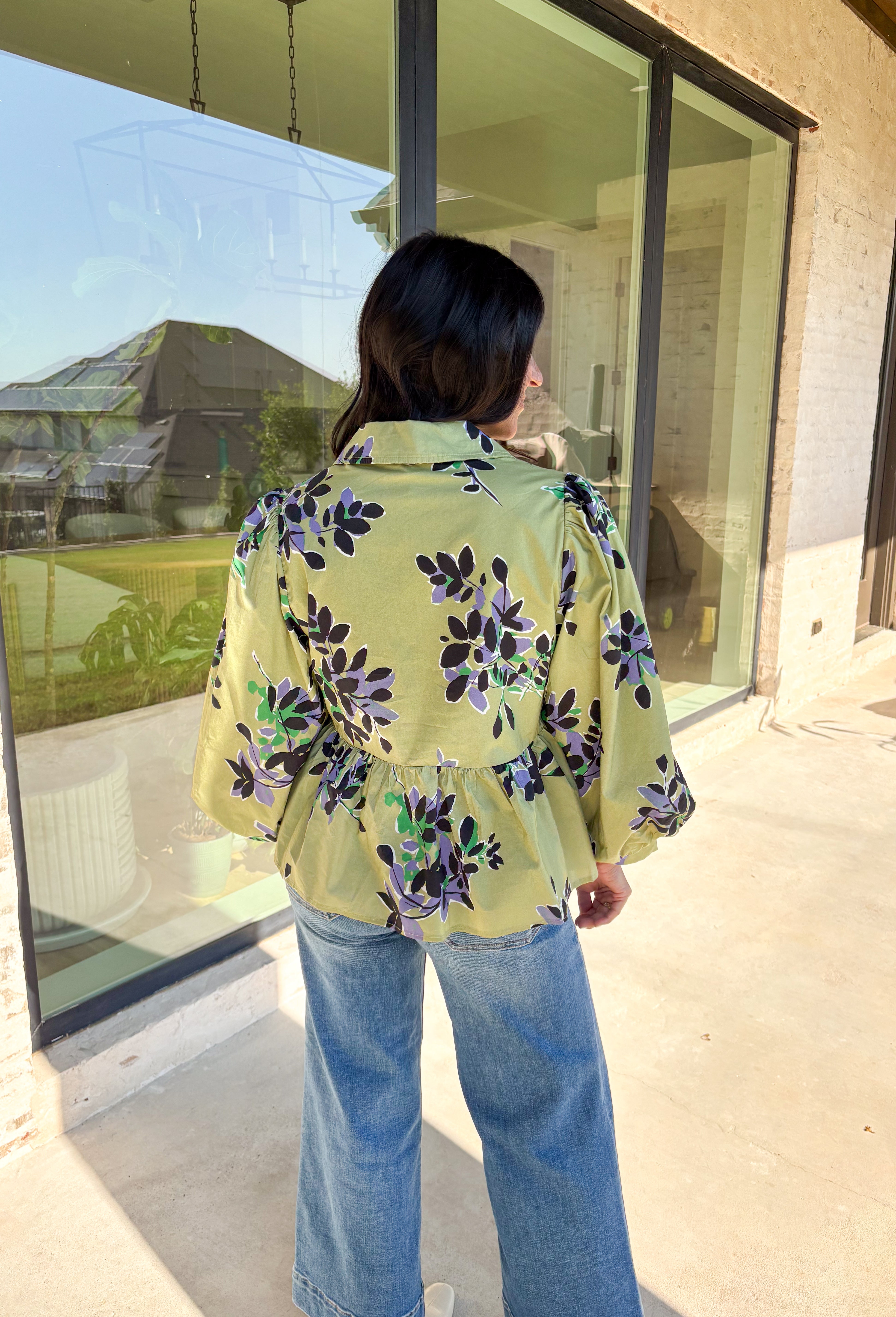 This olive long sleeve babydoll top features a striking black floral print with pops of purple, white, and green for a look that’s rich, moody, and totally wearable. The collared neckline adds a touch of polish, while the balloon sleeves bring in that breezy, romantic vibe. Made from 100% cotton, it’s breathable yet perfect for layering on crisp autumn days. Whether paired with denim or dress pants, this top easily goes from weekday to weekend.