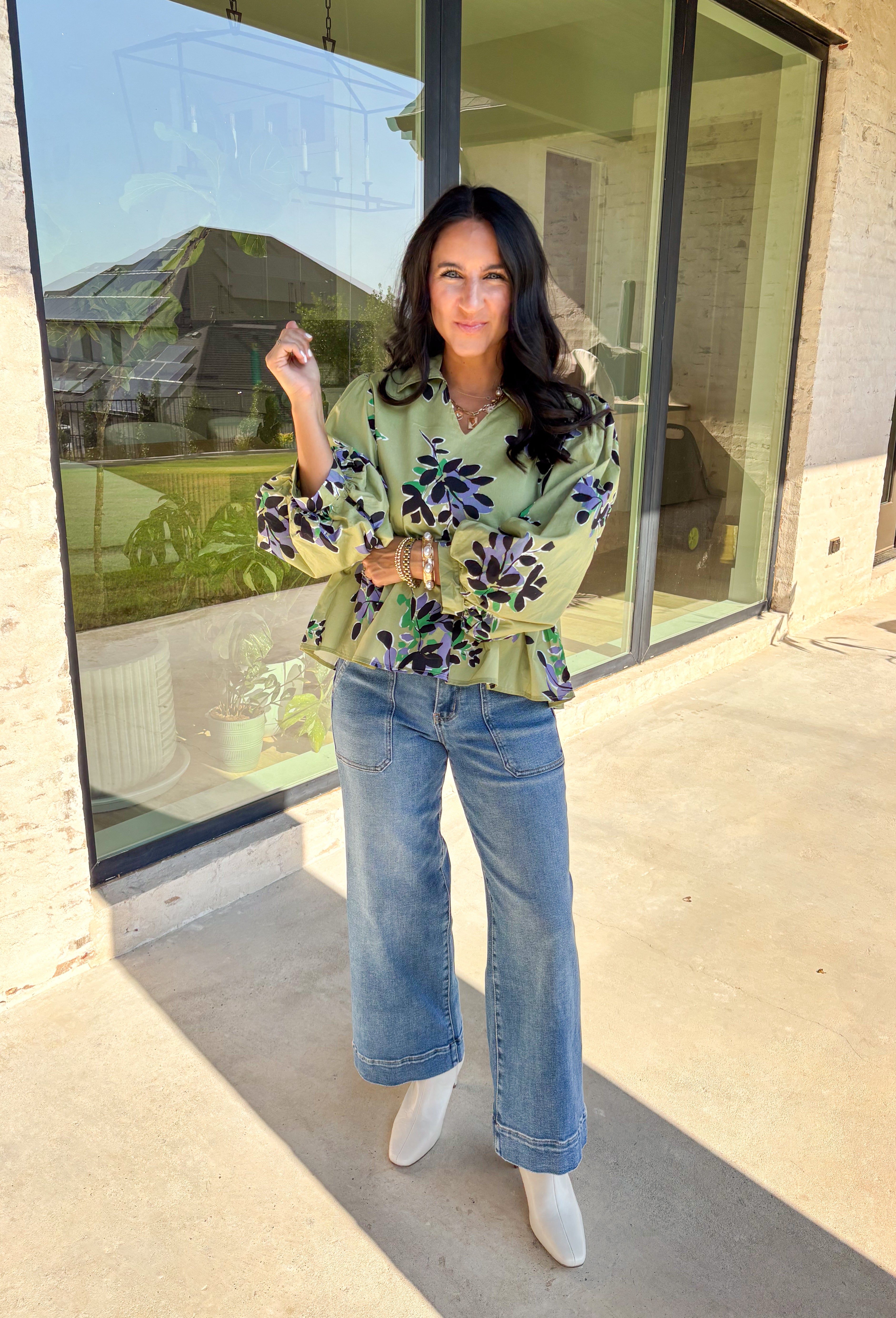 This olive long sleeve babydoll top features a striking black floral print with pops of purple, white, and green for a look that’s rich, moody, and totally wearable. The collared neckline adds a touch of polish, while the balloon sleeves bring in that breezy, romantic vibe. Made from 100% cotton, it’s breathable yet perfect for layering on crisp autumn days. Whether paired with denim or dress pants, this top easily goes from weekday to weekend.