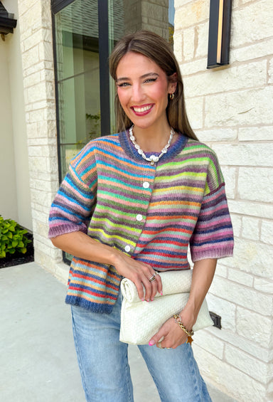 Who says fall has to be all neutrals? This cozy knit cardigan brings a cheerful burst of color to your seasonal wardrobe with bold stripes in green, pink, purple, yellow, blue, and orange. The button-down design gives you endless styling options—wear it buttoned as a sweater or open over your favorite basics for an effortless layered look. Crafted from a soft, cozy knit, it's the perfect piece to brighten crisp autumn days while keeping you comfortable from morning coffee runs to weekend adventures.
