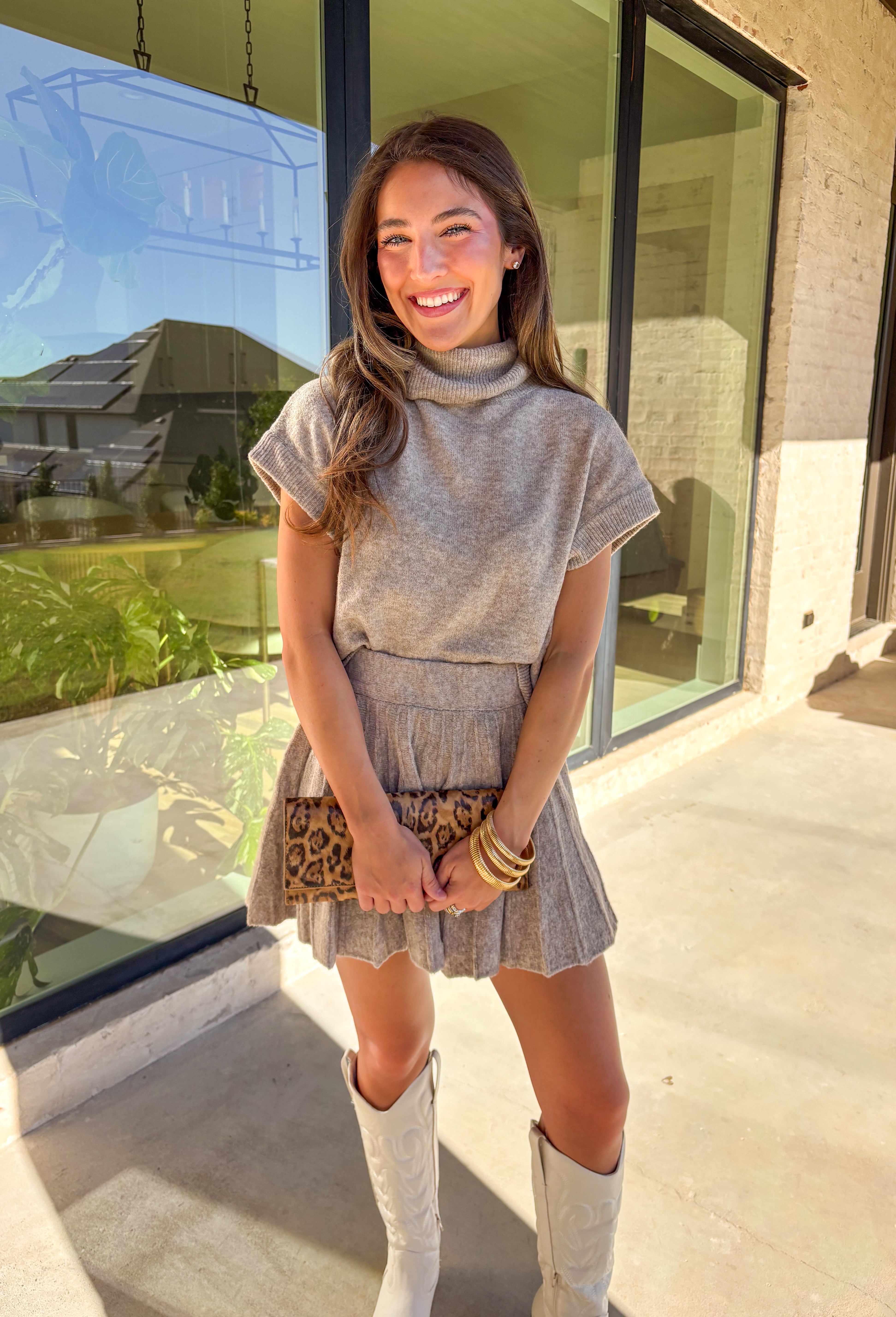 Chic meets cozy in this dark taupe two-piece set by Double Zero. Made from a soft, plush knit, this matching set features a short sleeve turtleneck sweater paired with a pleated skirt for an effortlessly put-together look. Whether you’re heading to brunch, the office, or a holiday gathering, this set gives you comfort and polish all in one.