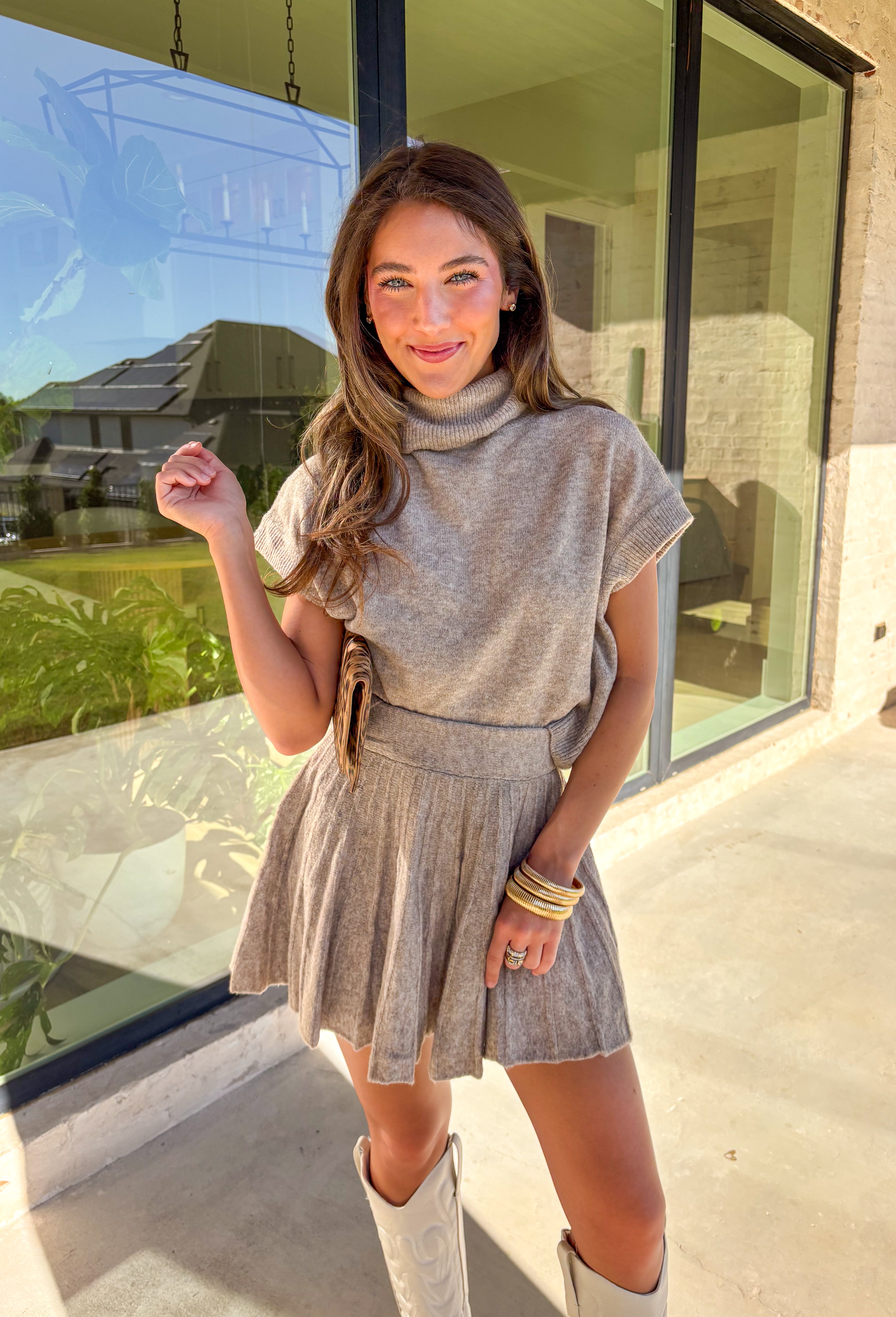 Chic meets cozy in this dark taupe two-piece set by Double Zero. Made from a soft, plush knit, this matching set features a short sleeve turtleneck sweater paired with a pleated skirt for an effortlessly put-together look. Whether you’re heading to brunch, the office, or a holiday gathering, this set gives you comfort and polish all in one.