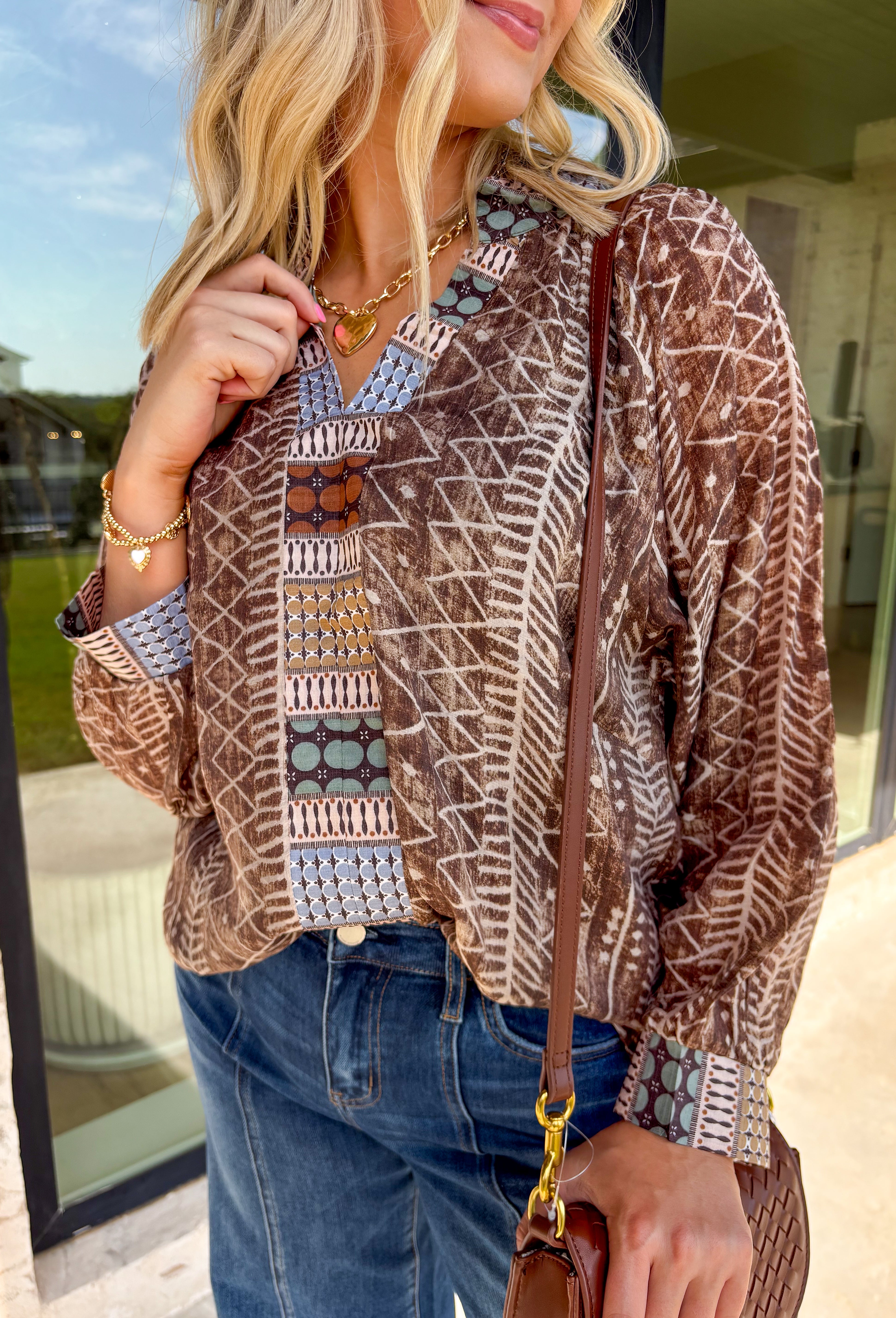 Add some artistic flair to your fall wardrobe with this brown and cream abstract print top. Designed with a contrasting abstract pattern at the neckline and along the front, it’s accented with subtle pops of tan, sage green, and charcoal for a fresh seasonal twist. Lightweight with a soft drape, it’s the kind of blouse that can be styled casually with denim or dressed up for workdays and evenings out.