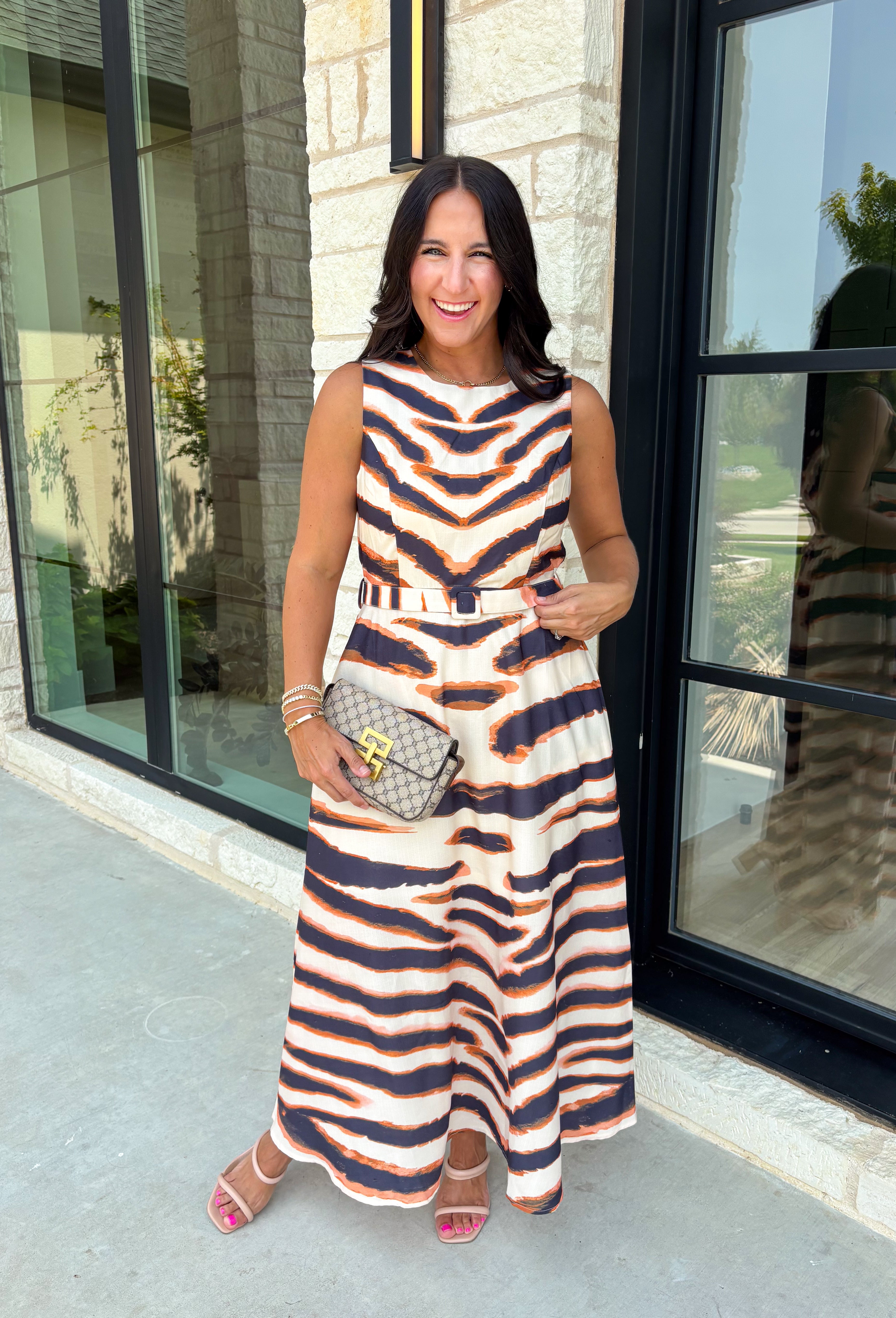 Turn heads this season in a midi dress that's equal parts bold and timeless. Featuring a neutral backdrop with an eye-catching black and orange tiger stripe print, this dress makes a statement while remaining effortlessly wearable. The belted waist creates a flattering silhouette, while side pockets and a fully lined design add comfort and practicality. Whether you're headed to brunch, family photos, or a fall event, this standout dress is ready for every occasion on your calendar.