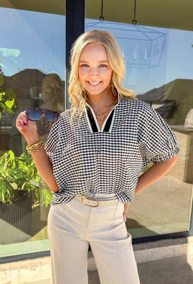 Sweet, fresh, and made for spring, this black and off-white gingham top by Entro is the perfect everyday pick-me-up. The gingham print gives it that classic, picnic-ready vibe, while the cream and black band along the top adds a clean contrast detail that makes it feel extra polished. Finished with elastic cuff sleeves for a comfortable fit, this top is lightweight, easy to style, and cute enough to wear on repeat all season long.