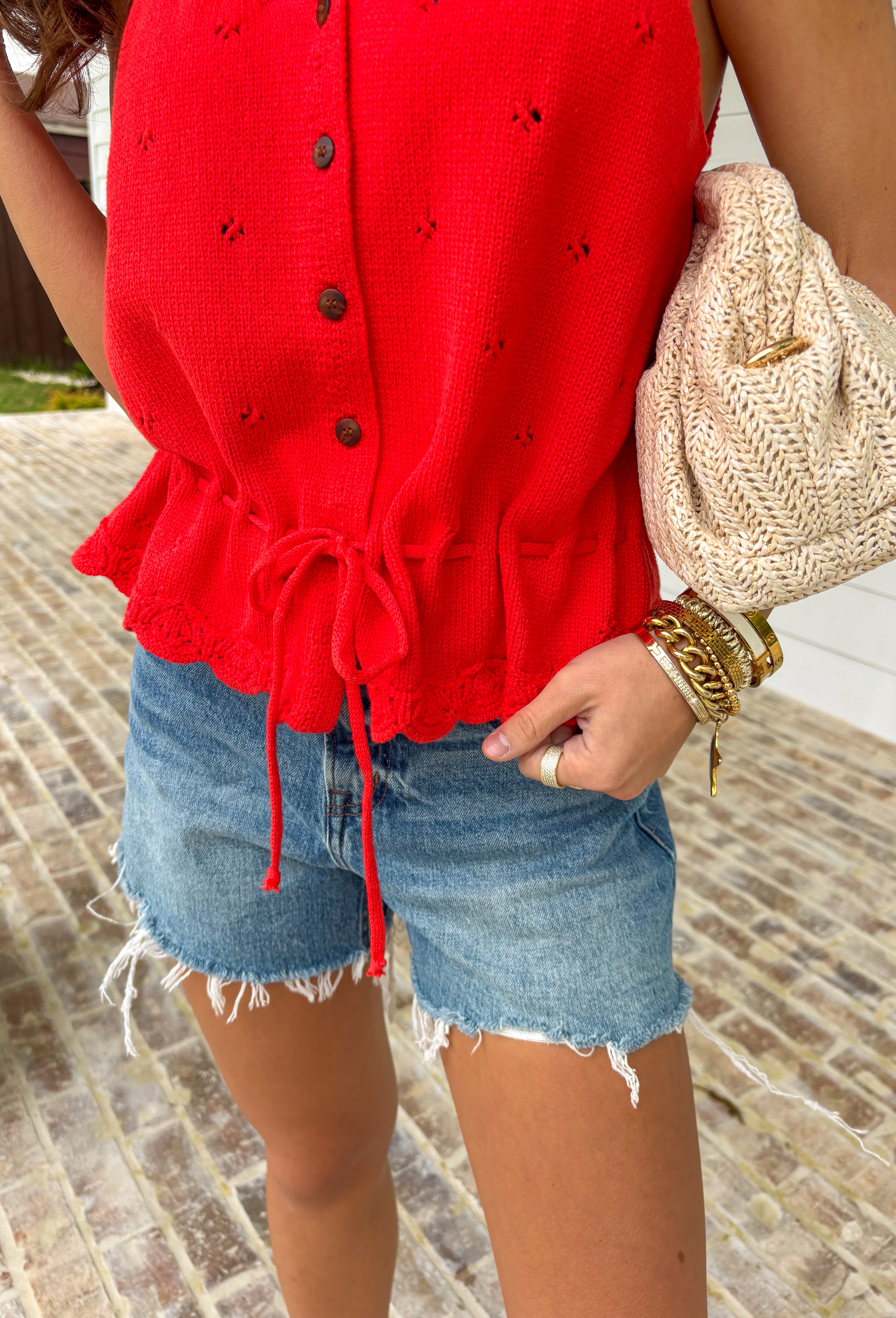 Add a pop of bold spring color to your closet with this red button down sweater tank by Wishlist! The open knit texture keeps it light and breathable, while the button-front design makes it easy to style solo or layered over a simple cami. Finished with the cutest scalloped hem and a tie detail at the bottom, this piece gives you that “effortlessly put together” look with just the right amount of playful charm. Pair it with light wash denim for an easy daytime outfit.