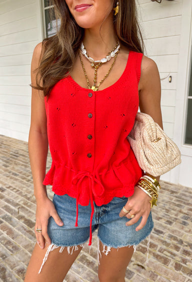 Add a pop of bold spring color to your closet with this red button down sweater tank by Wishlist! The open knit texture keeps it light and breathable, while the button-front design makes it easy to style solo or layered over a simple cami. Finished with the cutest scalloped hem and a tie detail at the bottom, this piece gives you that “effortlessly put together” look with just the right amount of playful charm. Pair it with light wash denim for an easy daytime outfit.