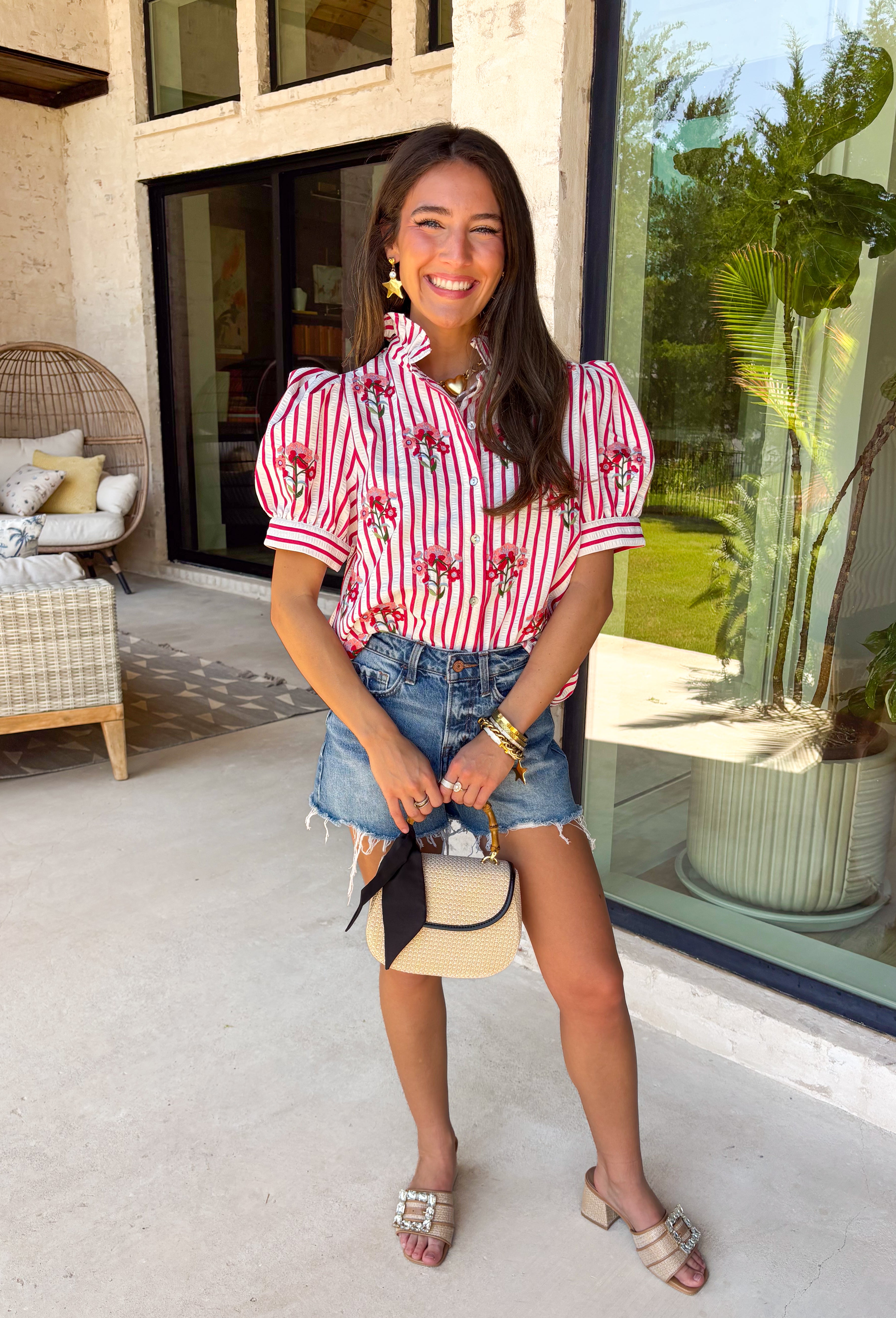 Nothing says sweet spring style quite like red and white stripes paired with cheerful florals. This striped short puff sleeve top by Entro brings playful charm and feminine detail together in the prettiest way. The classic red and white stripe base is brightened up with pink, red, green, and blue floral embroidery that adds texture, color, and that extra-special touch. Designed with a flattering button-front closure and soft puff sleeves, this top feels polished yet easy to wear. 