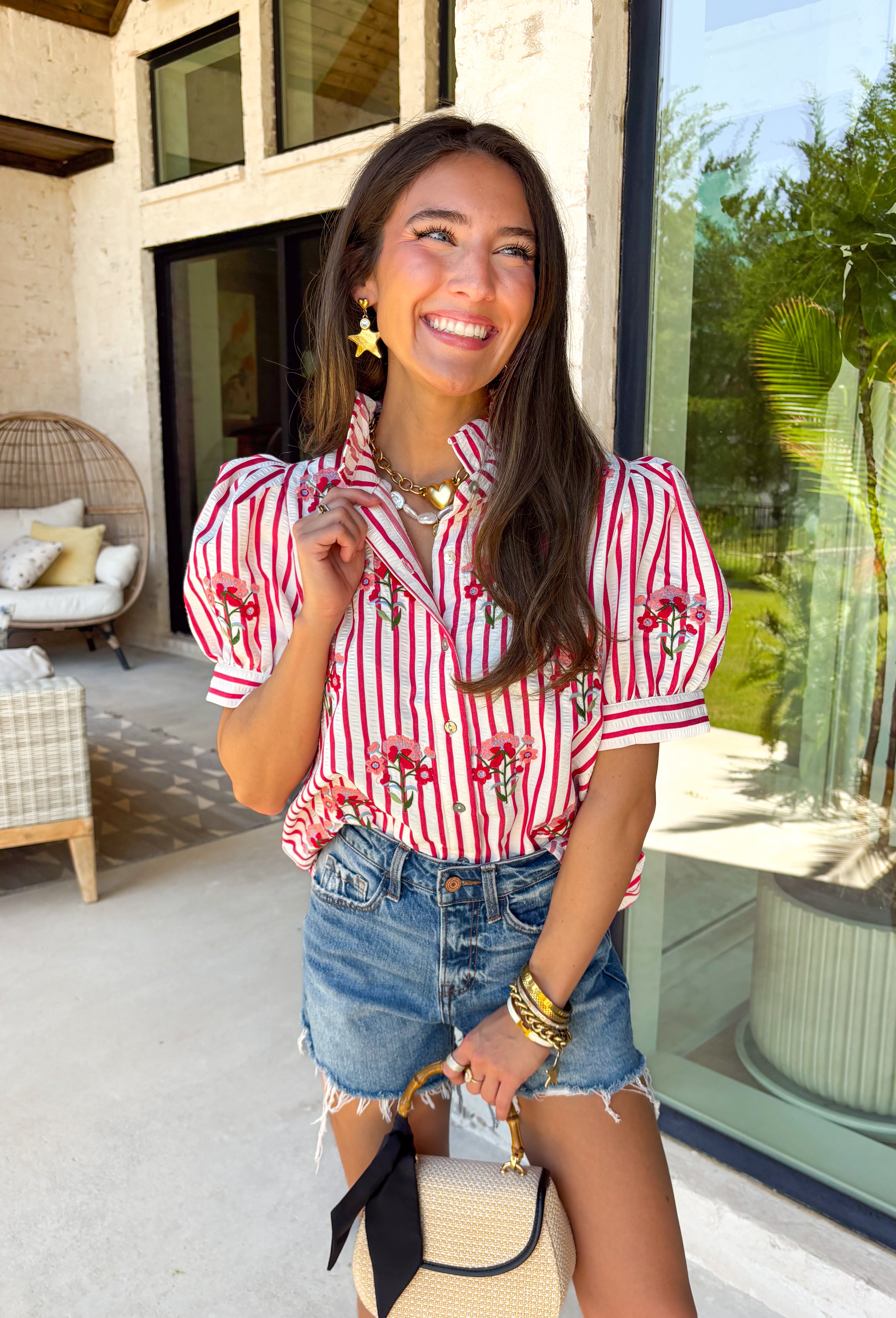 Nothing says sweet spring style quite like red and white stripes paired with cheerful florals. This striped short puff sleeve top by Entro brings playful charm and feminine detail together in the prettiest way. The classic red and white stripe base is brightened up with pink, red, green, and blue floral embroidery that adds texture, color, and that extra-special touch. Designed with a flattering button-front closure and soft puff sleeves, this top feels polished yet easy to wear. 
