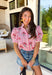 Nothing says sweet spring style quite like red and white stripes paired with cheerful florals. This striped short puff sleeve top by Entro brings playful charm and feminine detail together in the prettiest way. The classic red and white stripe base is brightened up with pink, red, green, and blue floral embroidery that adds texture, color, and that extra-special touch. Designed with a flattering button-front closure and soft puff sleeves, this top feels polished yet easy to wear. 