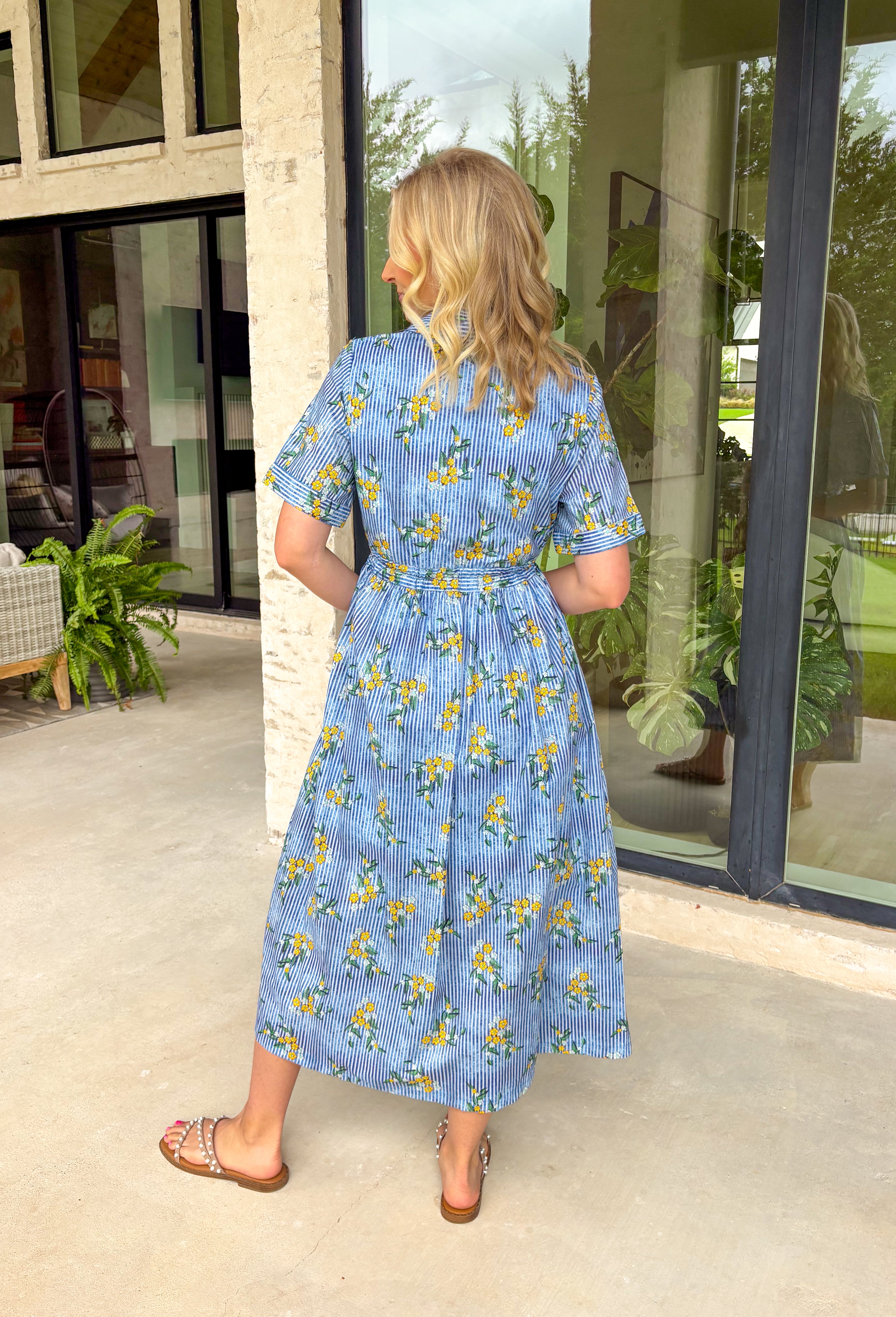 This blue striped midi dress is the perfect blend of classic and cheerful for summer! The blue stripe print creates a timeless foundation, while the yellow floral pattern adds a bright, sunny pop that instantly stands out. Designed with a collared neckline and button front closure, it has a polished feel that's easy to dress up or down. The adjustable drawstring waist creates a flattering silhouette, and side pockets make it even better. 