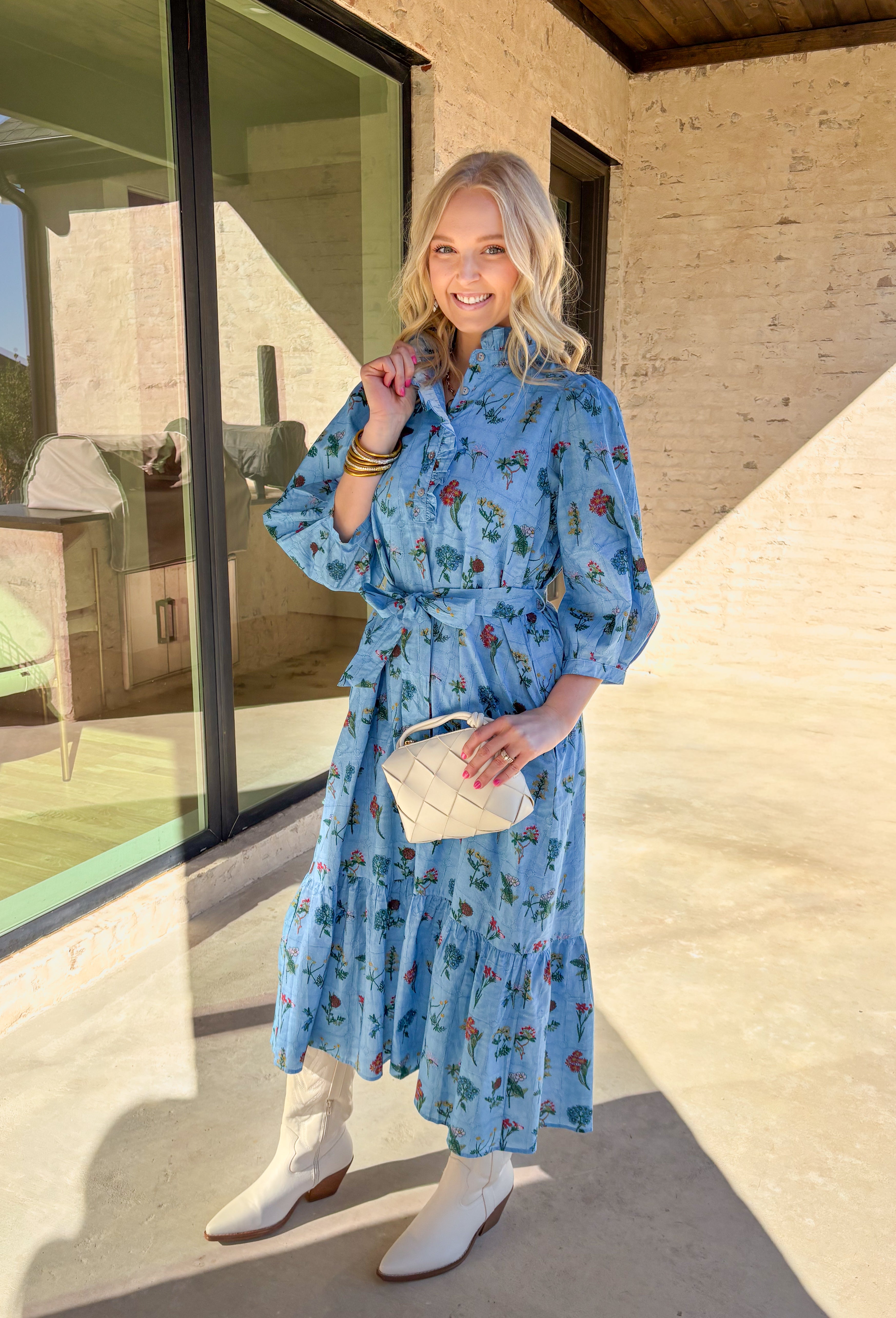 Colorful, charming, and full of spring personality, this blue midi dress by Entro is a true standout. Featuring a patchwork-style floral print with a mix of bright, happy colors, it feels playful yet polished. The ruffle neckline and front button details add a soft, feminine touch, while the 3/4 length sleeves and matching self-tie waist create a flattering, easy fit. Fully lined and made from breathable cotton, this dress is perfect for brunch, spring events, and everything in between.