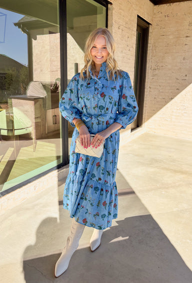 Colorful, charming, and full of spring personality, this blue midi dress by Entro is a true standout. Featuring a patchwork-style floral print with a mix of bright, happy colors, it feels playful yet polished. The ruffle neckline and front button details add a soft, feminine touch, while the 3/4 length sleeves and matching self-tie waist create a flattering, easy fit. Fully lined and made from breathable cotton, this dress is perfect for brunch, spring events, and everything in between.