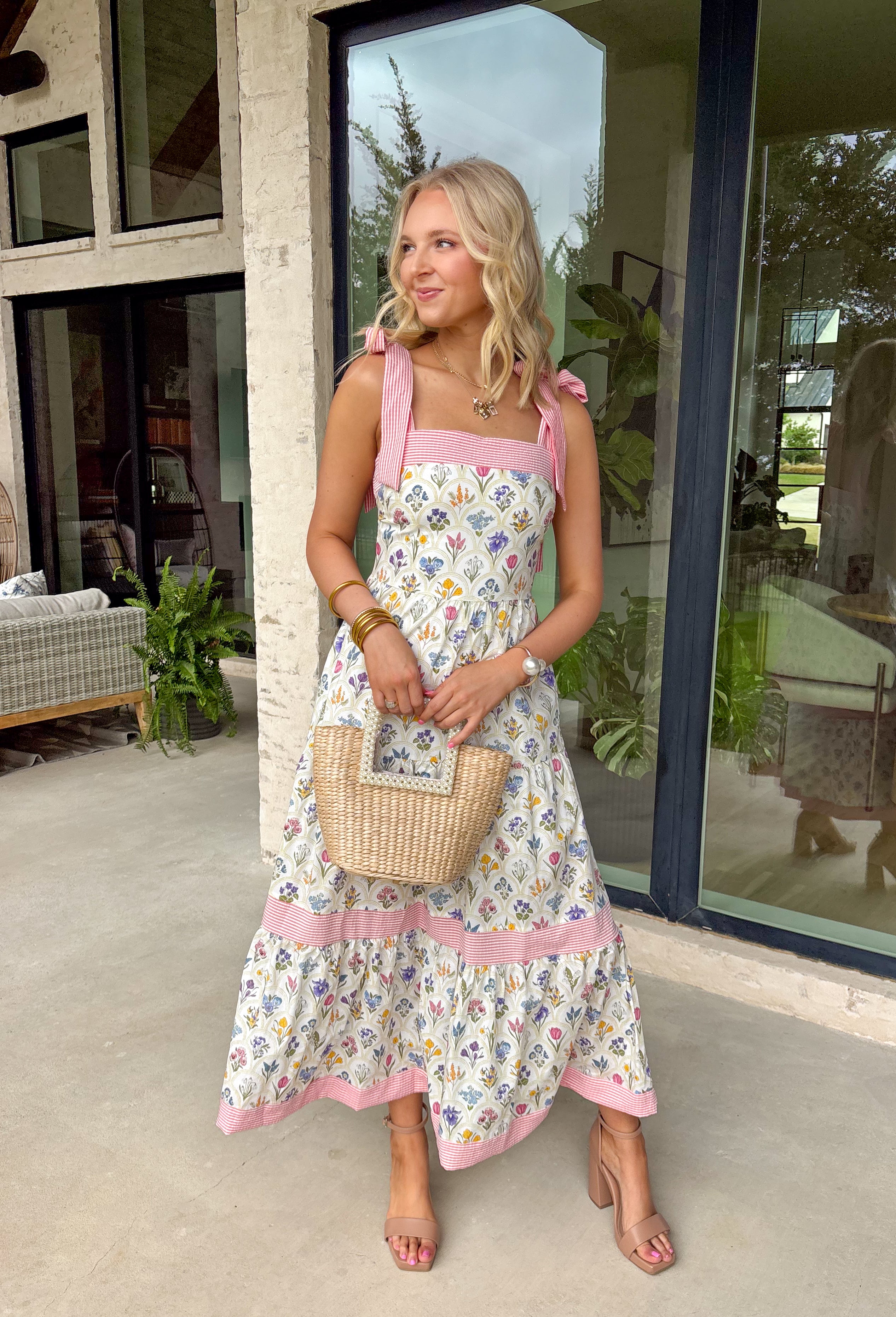 Fresh, colorful, and made for sunny days! This neutral tiered dress features a vibrant floral print with pops of pink, yellow, purple, blue, and green for a cheerful, eye-catching look. The flowy tiered silhouette adds beautiful movement, while the pink and white stripe trim throughout gives it an extra playful touch. The adjustable tie straps not only add a sweet detail but also allow for a customizable fit. Lightweight and fully lined, this dress is perfect for everything.