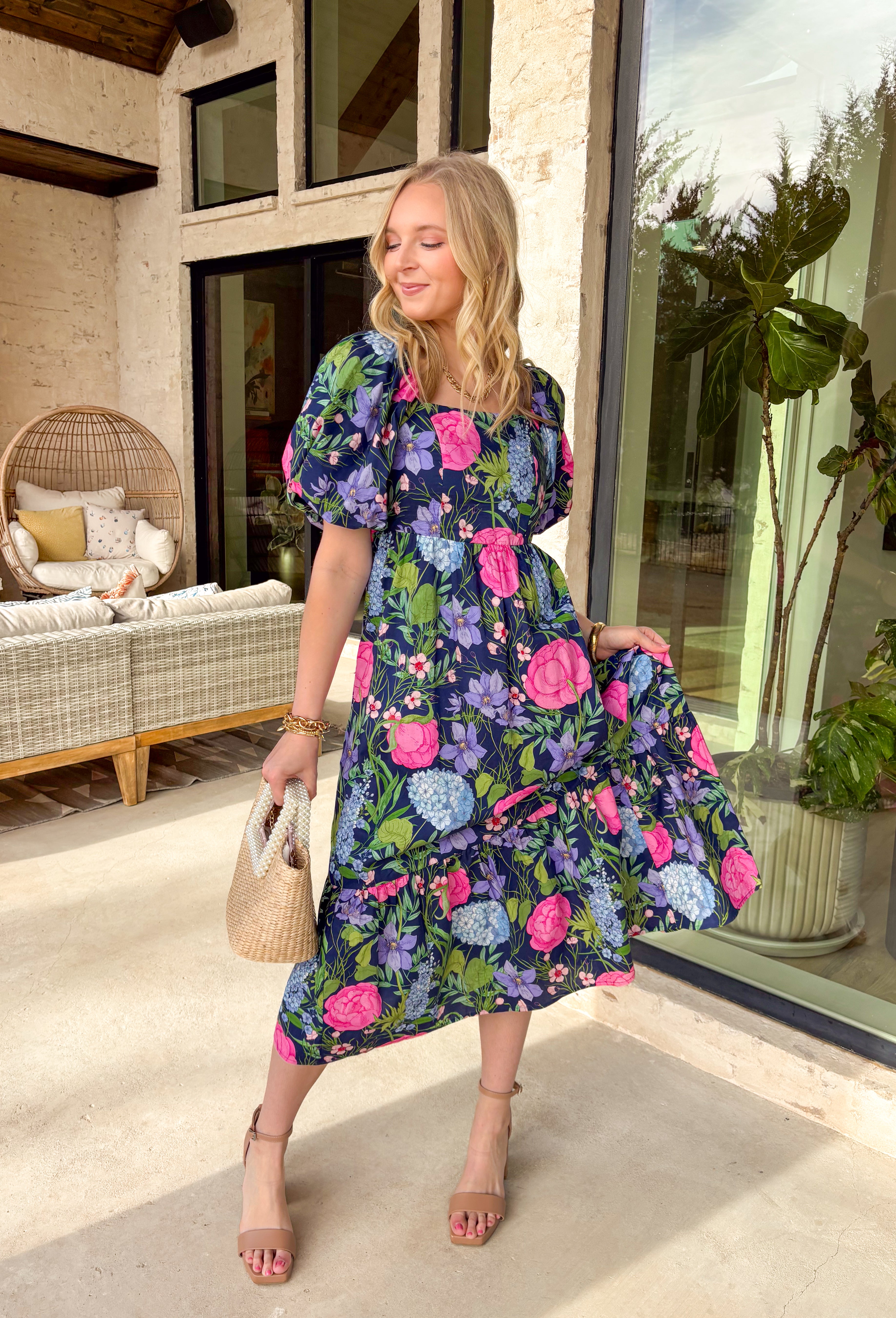 Colorful, flowy, and made for spring days, this navy short sleeve midi dress is an instant favorite. Featuring a vibrant floral print with pops of pink, green, blue, and purple, it brings the perfect burst of color against a classic navy base. The square neckline feels modern and flattering, while puff sleeves add a soft, feminine touch. A tiered skirt gives it beautiful movement, and smocking at the back with a tie closure ensures a comfortable, adjustable fit. 
