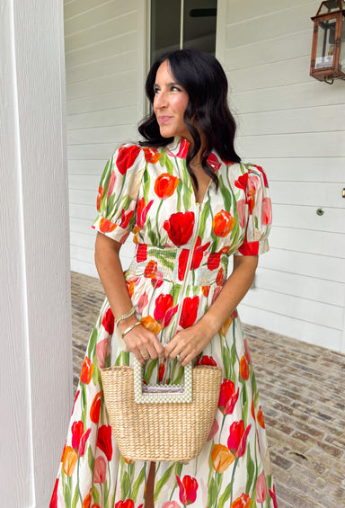 Bright blooms and easy details make this neutral short sleeve midi dress by Entro a spring favorite. Featuring a bold tulip floral print with vibrant pops of red, green, and orange, it brings cheerful color to a soft, wearable base. Puff sleeves add a feminine touch, while the front zipper closure gives it a modern, effortless feel. An elastic waist creates a flattering fit, and the full lining keeps it comfortable all day long. This is the kind of dress that does all the work—just add sunshine.