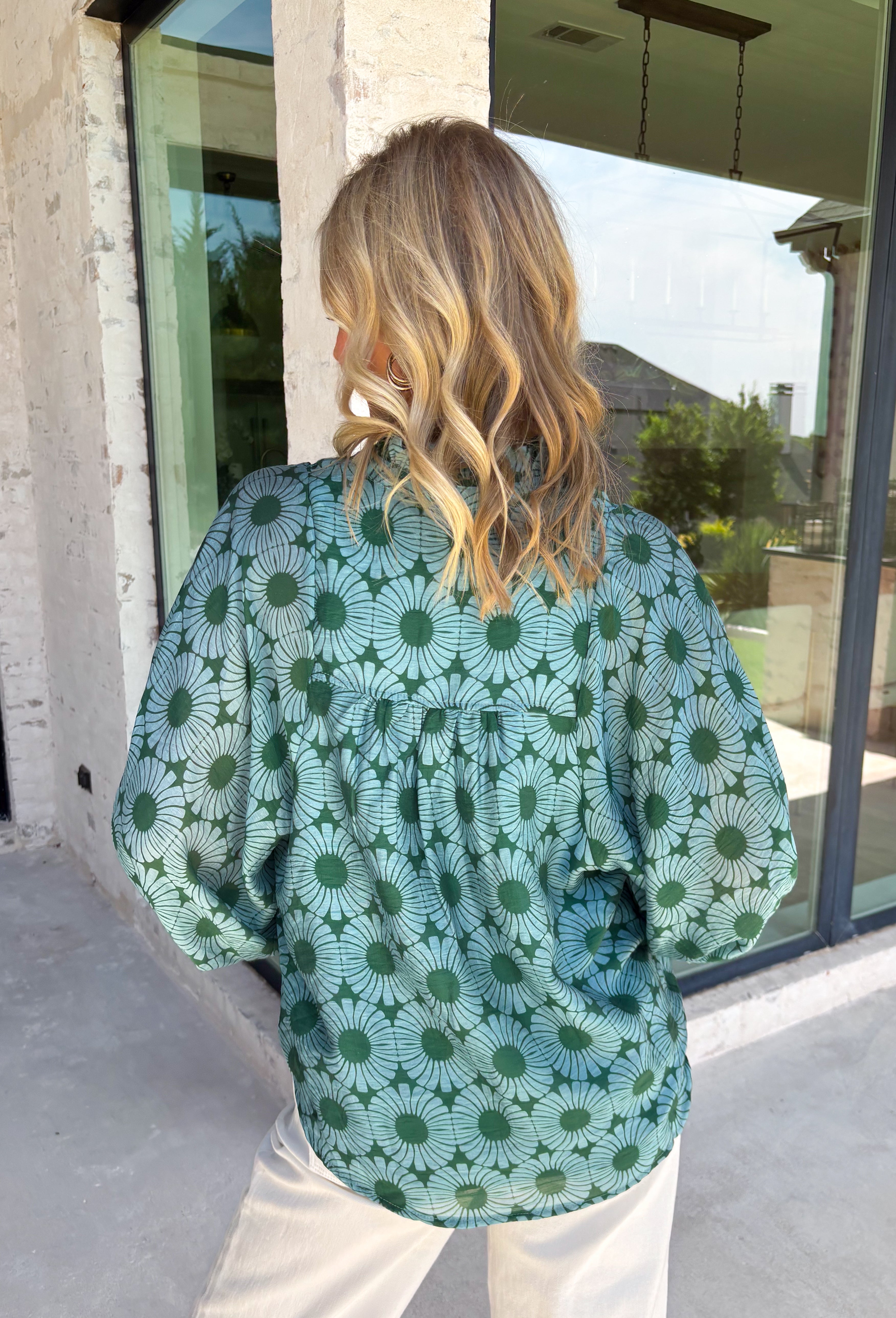 Bring fresh color to your fall wardrobe with this effortlessly beautiful floral blouse. Featuring a rich hunter green backdrop with a bold light blue floral print, this top is the perfect blend of classic and feminine. The subtle ruffle neckline adds a soft, romantic touch, while the button-down design makes it easy to style for both work and weekends. Crafted from a breathable tencel, linen, and nylon blend.