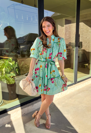 This green and white striped dress is spring sunshine in outfit form. Featuring a colorful floral print with pops of yellow, orange, pink, and purple, it’s the perfect mix of classic and cheerful. The collared neckline and gold button-down front give it a polished touch, while the matching self-tie belt cinches the waist for a flattering, adjustable fit. Fully lined and made from breathable cotton, this dress is ready for brunch dates, spring events, and every sunny-day plan in between.