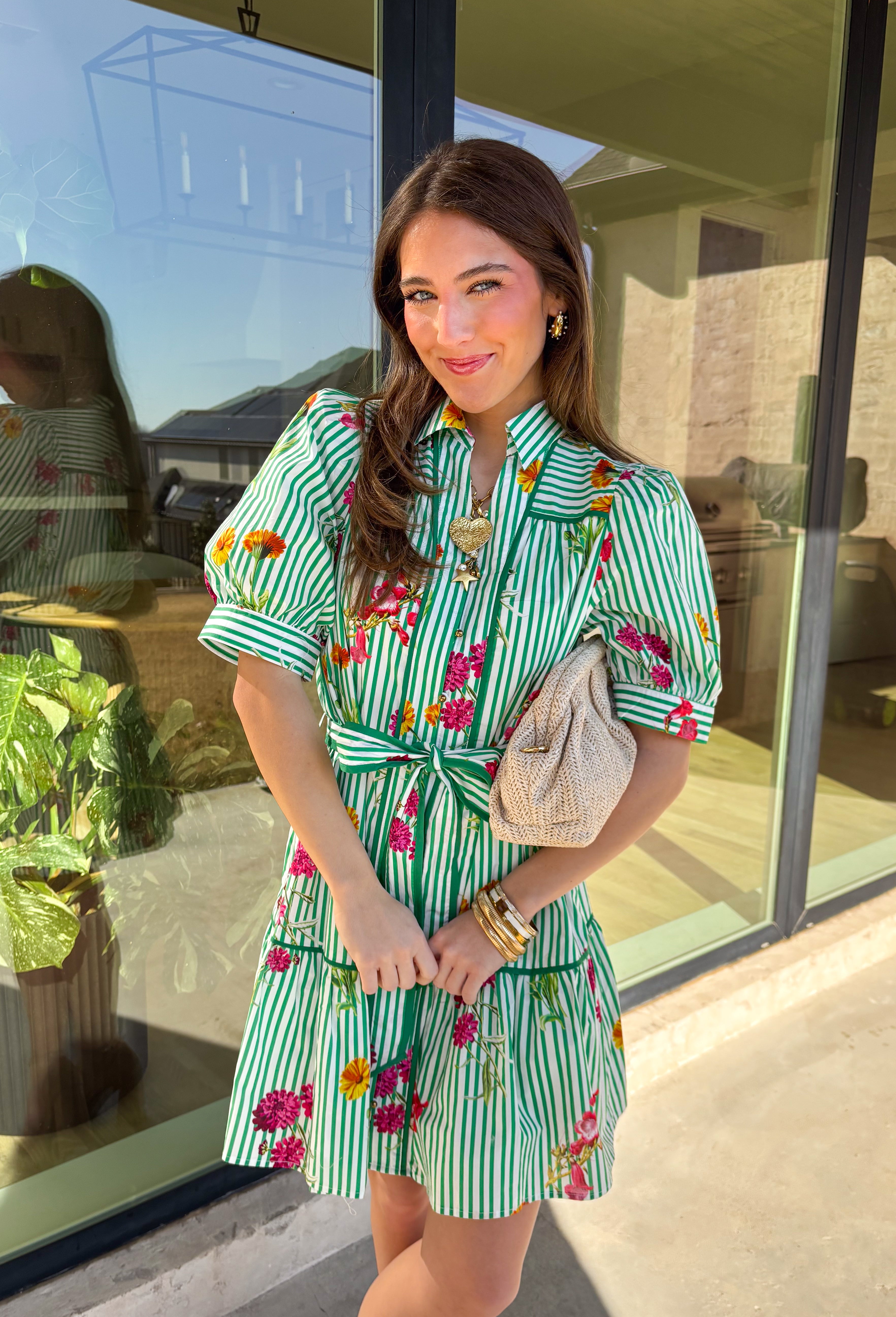 This green and white striped dress is spring sunshine in outfit form. Featuring a colorful floral print with pops of yellow, orange, pink, and purple, it’s the perfect mix of classic and cheerful. The collared neckline and gold button-down front give it a polished touch, while the matching self-tie belt cinches the waist for a flattering, adjustable fit. Fully lined and made from breathable cotton, this dress is ready for brunch dates, spring events, and every sunny-day plan in between.