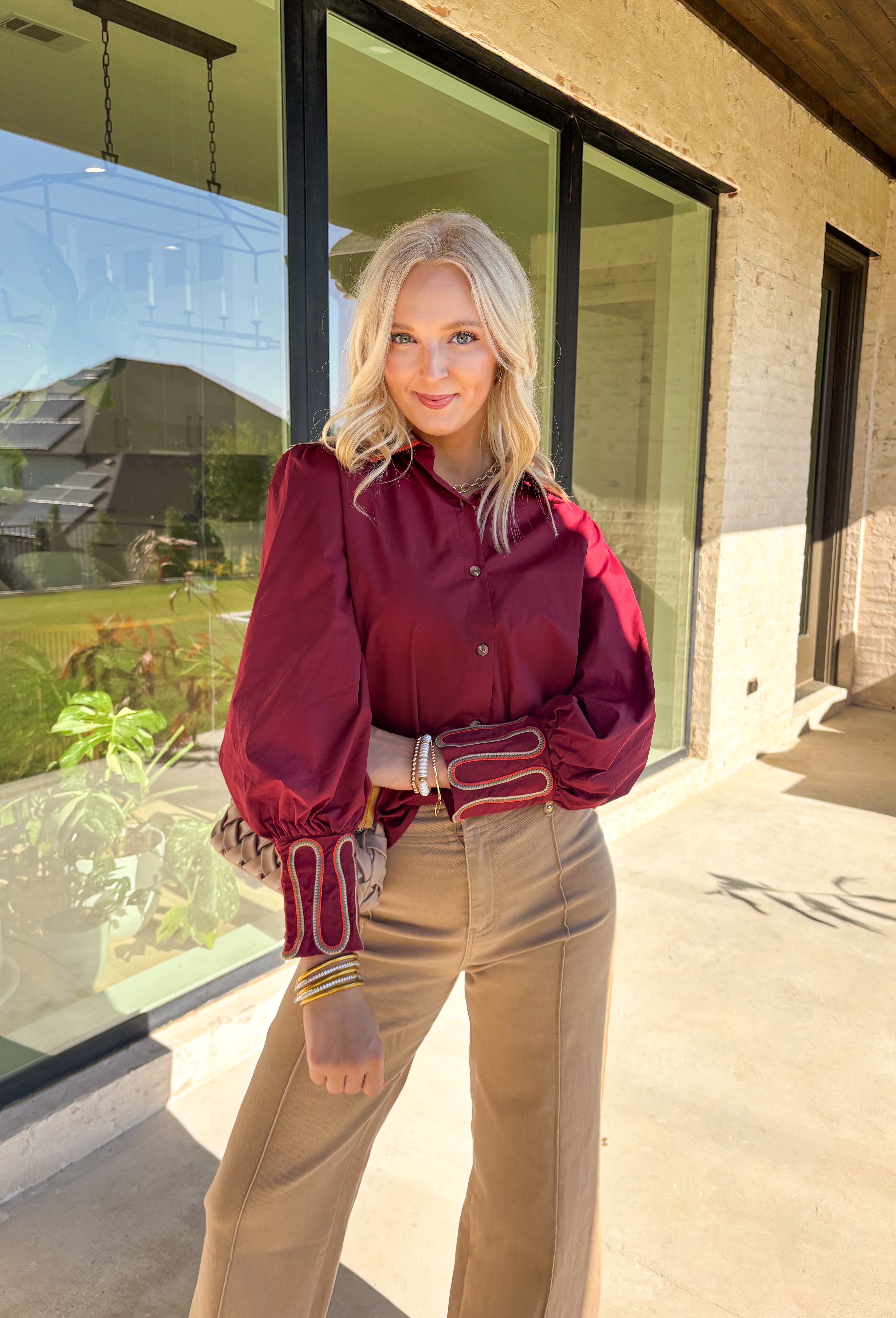 This burgundy button-down top by Jodifl brings unique embroidered detailing to a classic silhouette. The collar features intricate embroidery in olive, rust, and tan, while the sleeves showcase a coordinating abstract embroidered design in the same earthy tones—adding contrast and personality to the look. Crafted from 100% cotton, it’s breathable, lightweight, and perfect for styling through the season.
