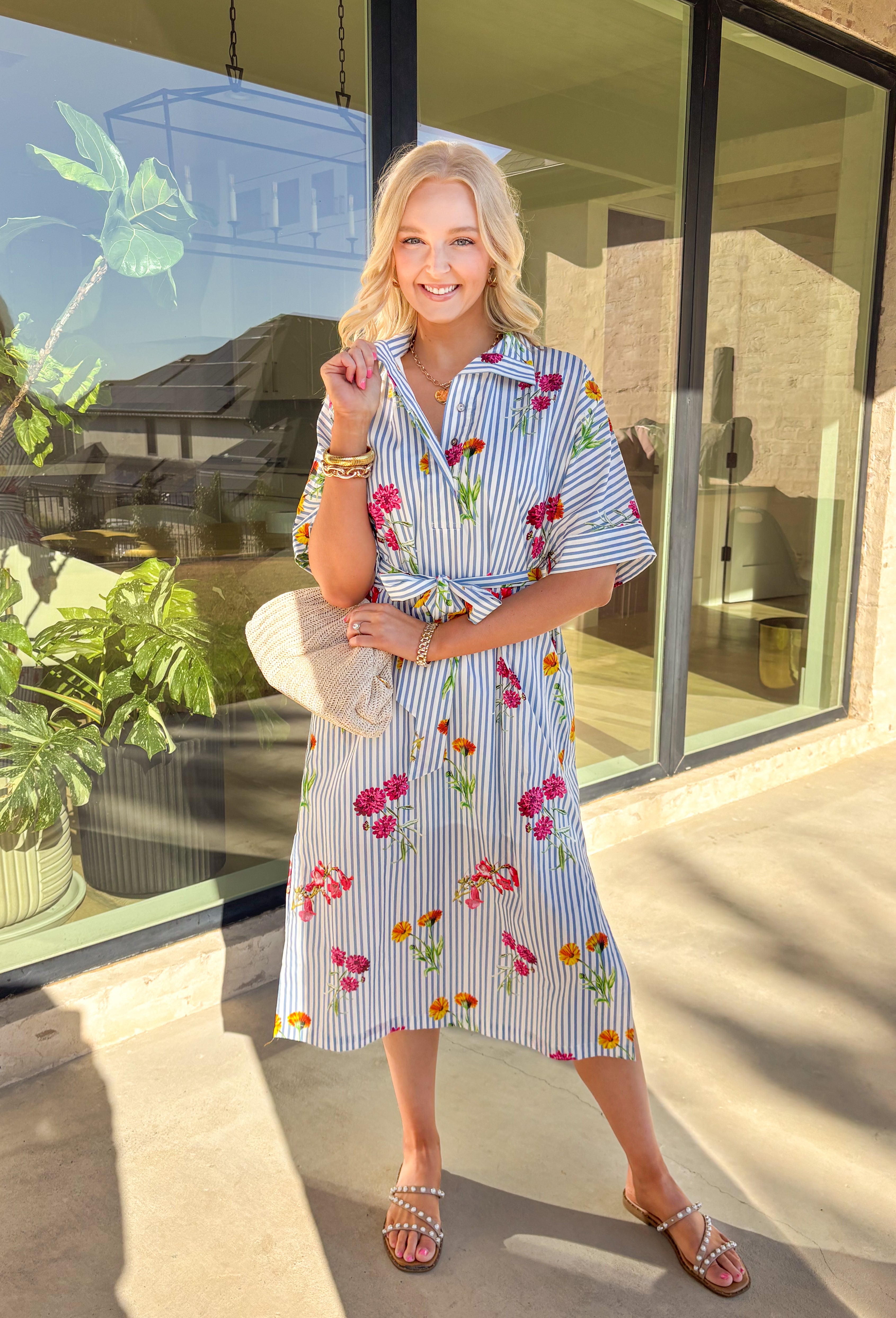 Classic stripes meet spring florals in this blue and white striped midi dress—an effortless favorite for sunny days ahead. Featuring a colorful floral print throughout, it adds the perfect pop of color to a timeless silhouette. The collared neckline and short sleeves keep it polished, while the matching self-tie waist creates a flattering, adjustable fit. Finished with side slits for easy movement and a full lining for comfortable wear, this dress is ready for brunch, showers, and spring weekends.