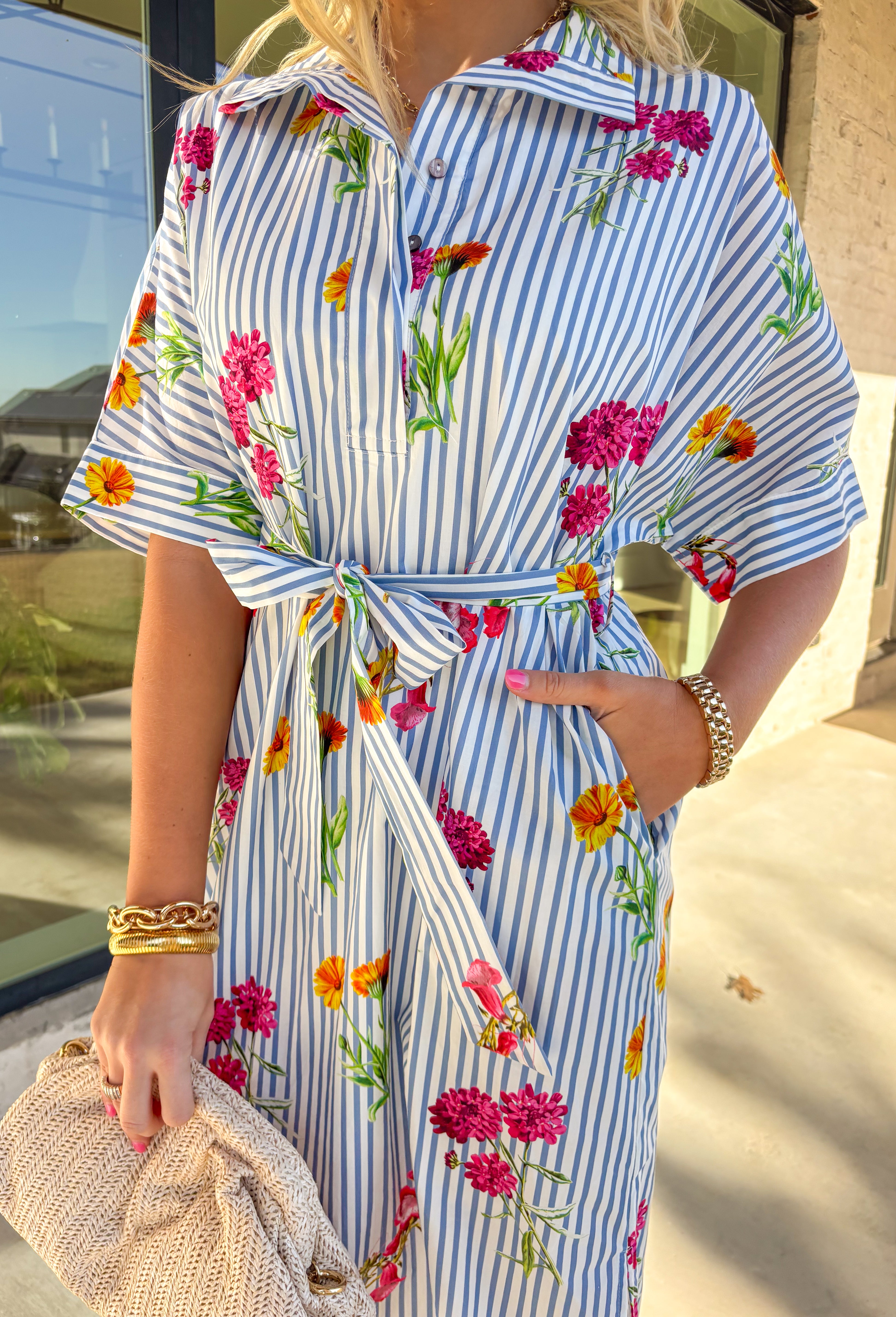 Classic stripes meet spring florals in this blue and white striped midi dress—an effortless favorite for sunny days ahead. Featuring a colorful floral print throughout, it adds the perfect pop of color to a timeless silhouette. The collared neckline and short sleeves keep it polished, while the matching self-tie waist creates a flattering, adjustable fit. Finished with side slits for easy movement and a full lining for comfortable wear, this dress is ready for brunch, showers, and spring weekends.