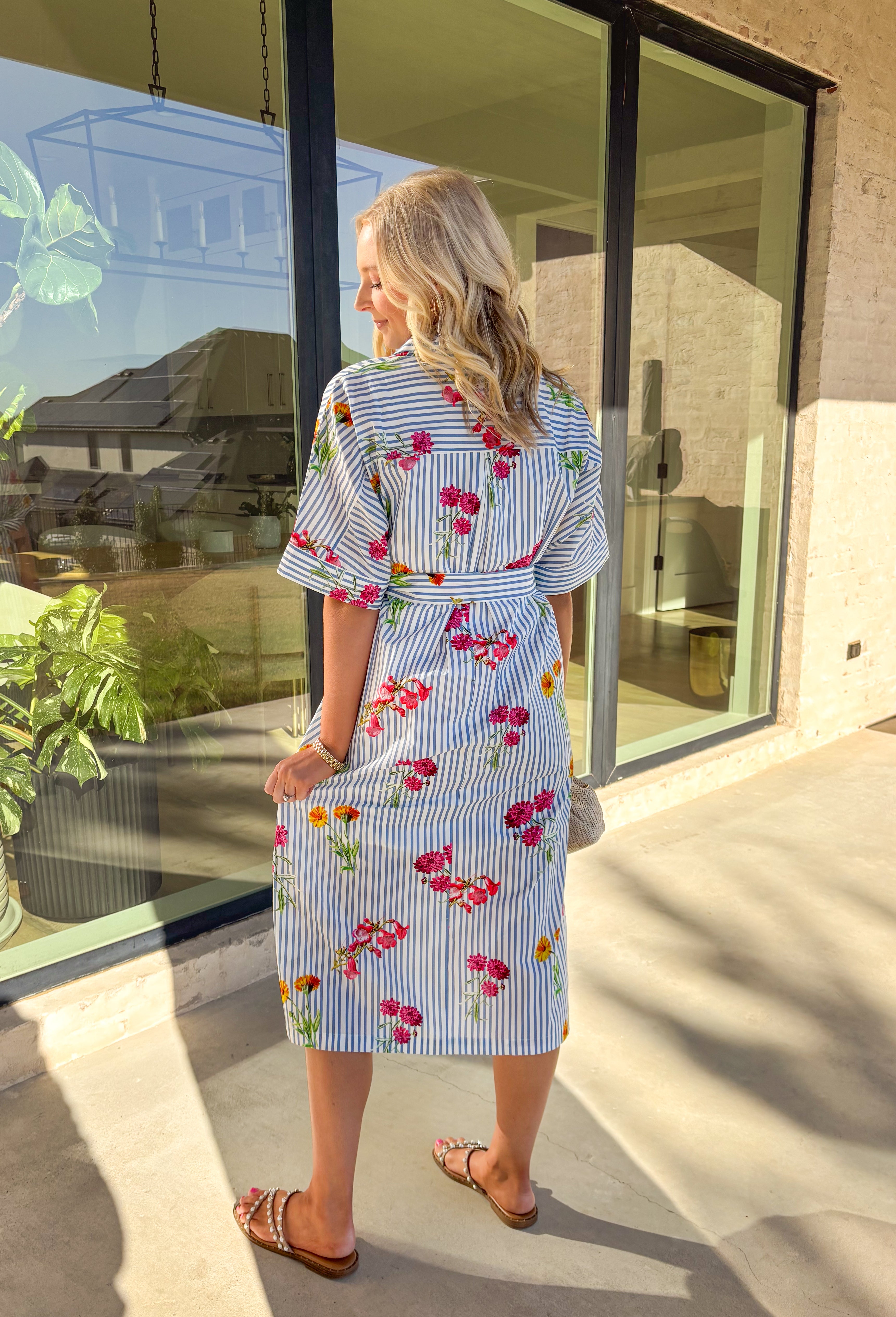 Classic stripes meet spring florals in this blue and white striped midi dress—an effortless favorite for sunny days ahead. Featuring a colorful floral print throughout, it adds the perfect pop of color to a timeless silhouette. The collared neckline and short sleeves keep it polished, while the matching self-tie waist creates a flattering, adjustable fit. Finished with side slits for easy movement and a full lining for comfortable wear, this dress is ready for brunch, showers, and spring weekends.