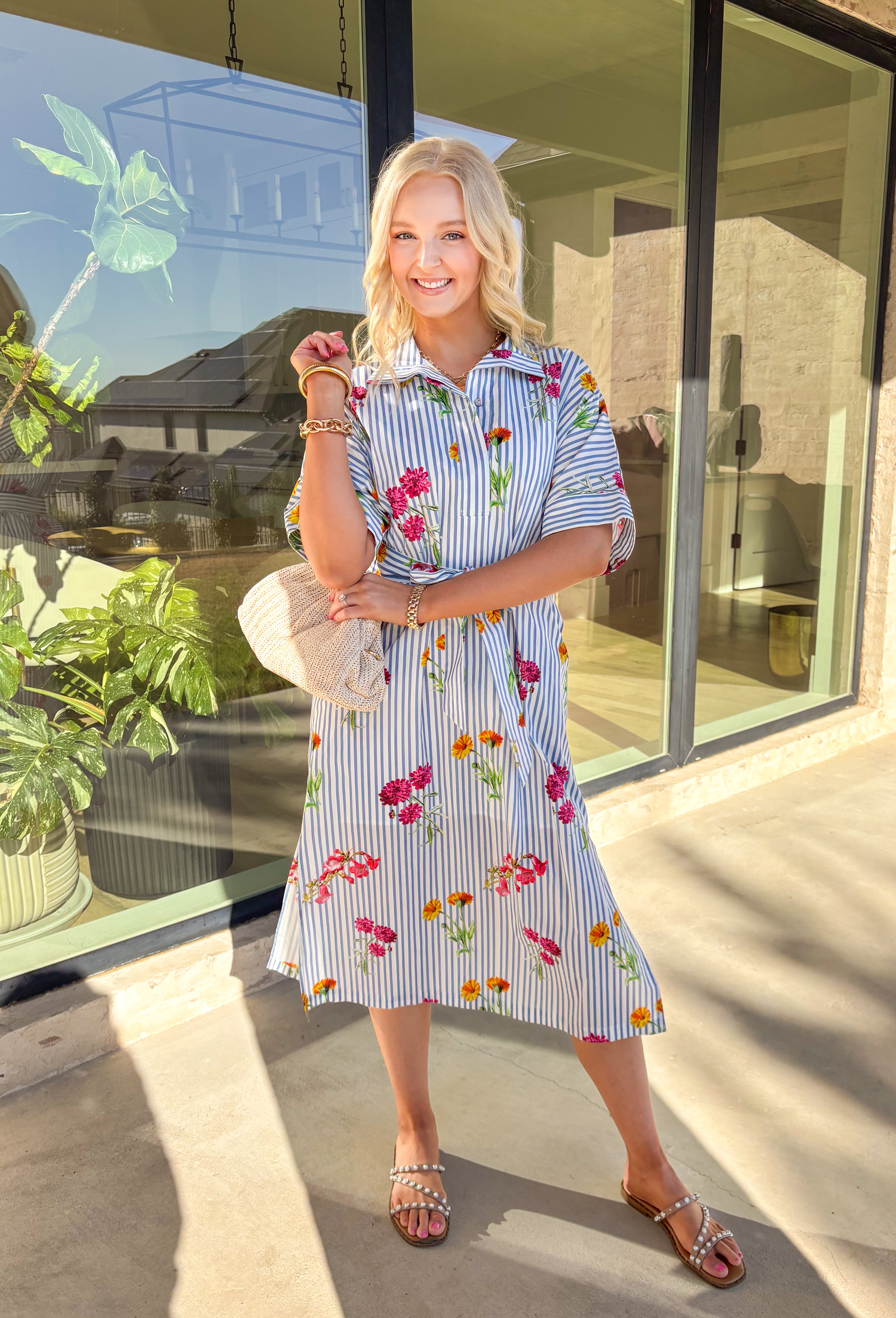 Classic stripes meet spring florals in this blue and white striped midi dress—an effortless favorite for sunny days ahead. Featuring a colorful floral print throughout, it adds the perfect pop of color to a timeless silhouette. The collared neckline and short sleeves keep it polished, while the matching self-tie waist creates a flattering, adjustable fit. Finished with side slits for easy movement and a full lining for comfortable wear, this dress is ready for brunch, showers, and spring weekends.