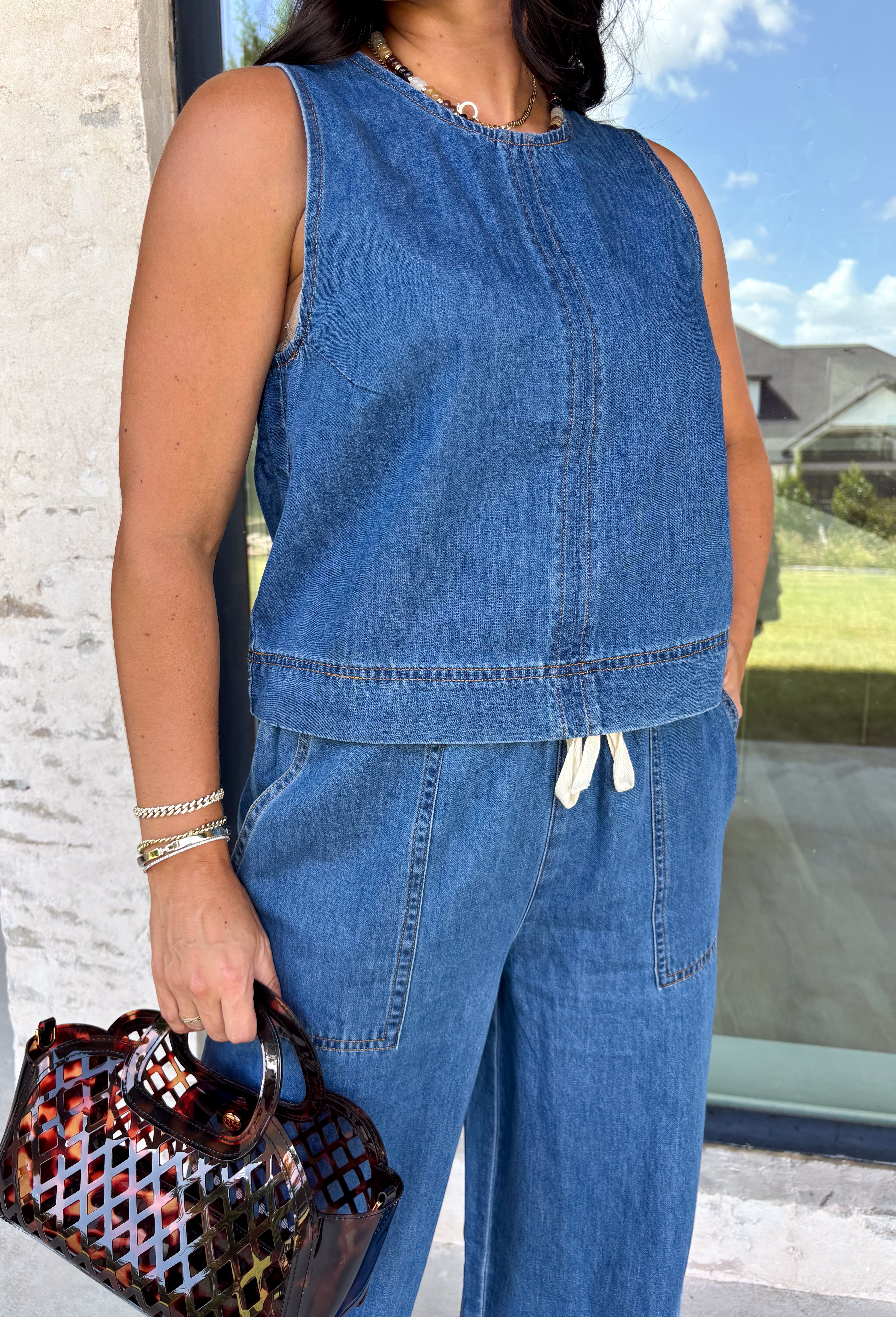 Double denim has never been easier with this matching two-piece set from Tres Bien. The sleeveless medium wash denim top features contrasting tan stitching throughout, giving the classic denim look a little extra detail. Coordinating wide leg jeans complete the set with an easy, relaxed silhouette, while the elastic waistband and adjustable self-tie detail keep the fit comfortable throughout the day. 