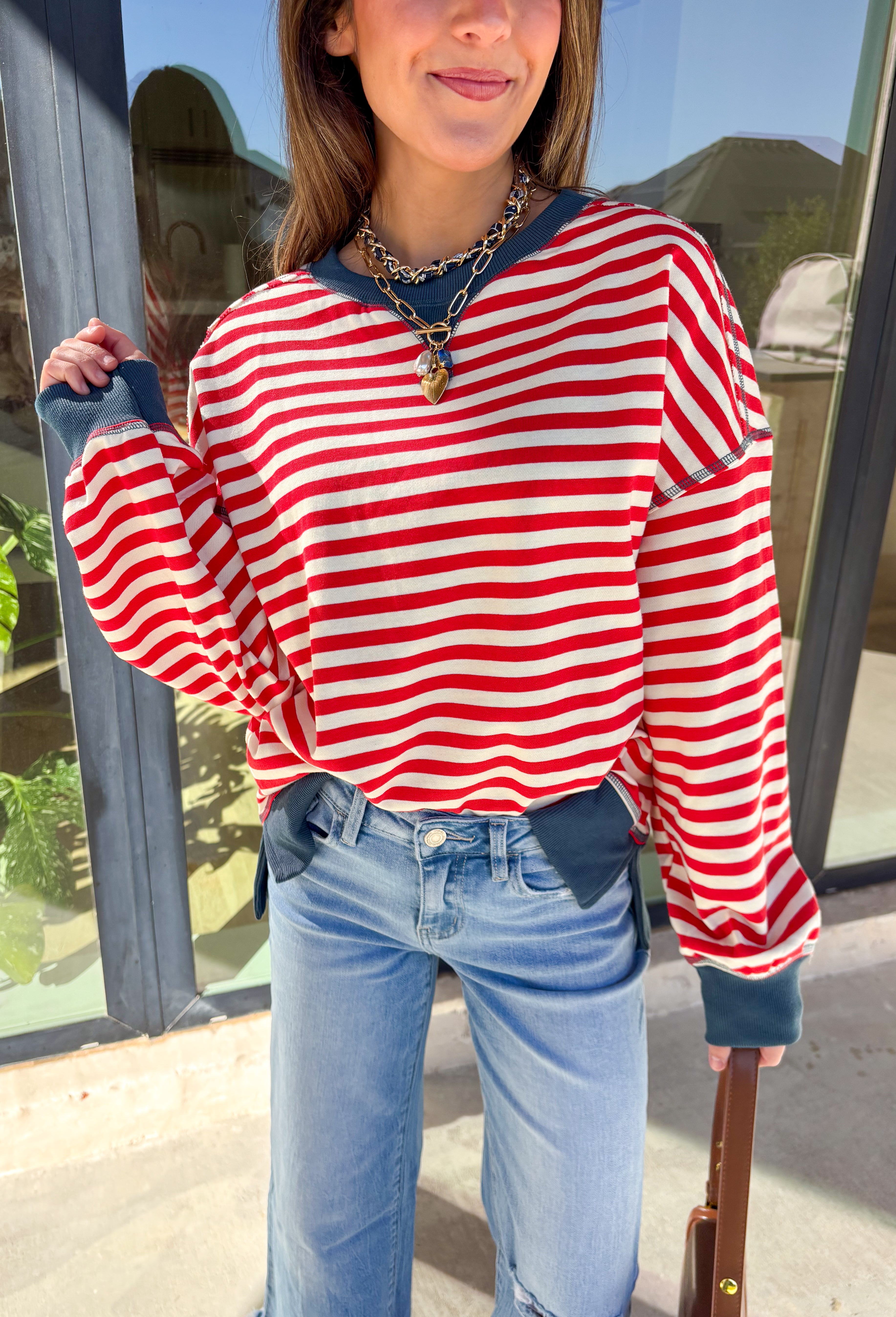 Stay cozy in classic stripes with this red and off-white pullover by New In. Designed with navy blue trim along the neckline, cuffs, and stitching, this lightweight knit brings a timeless touch to chilly days. Soft, comfortable, and easy to layer, it’s perfect for transitioning from crisp mornings to cozy evenings all winter long.