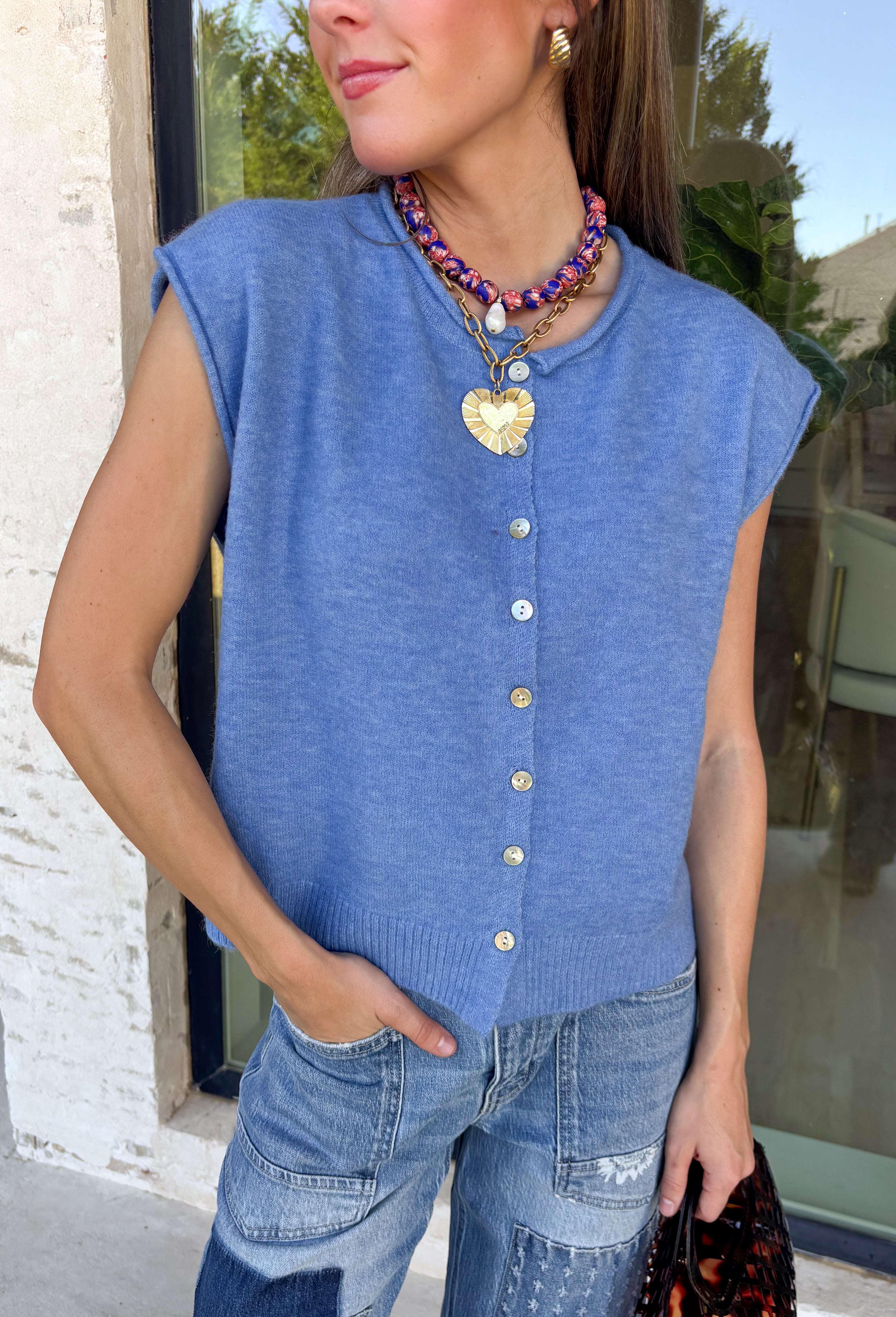Layering season calls for pieces that can keep up with changing temperatures, and this blue sleeveless cardigan from Double Zero is ready for just that. The cozy knit brings plenty of texture and warmth, while the sleeveless design makes it easy to wear alone on milder days or layer over a long sleeve top as winter gets closer. A button-down front gives you multiple ways to style it, and the ribbed hem adds a classic sweater finish.