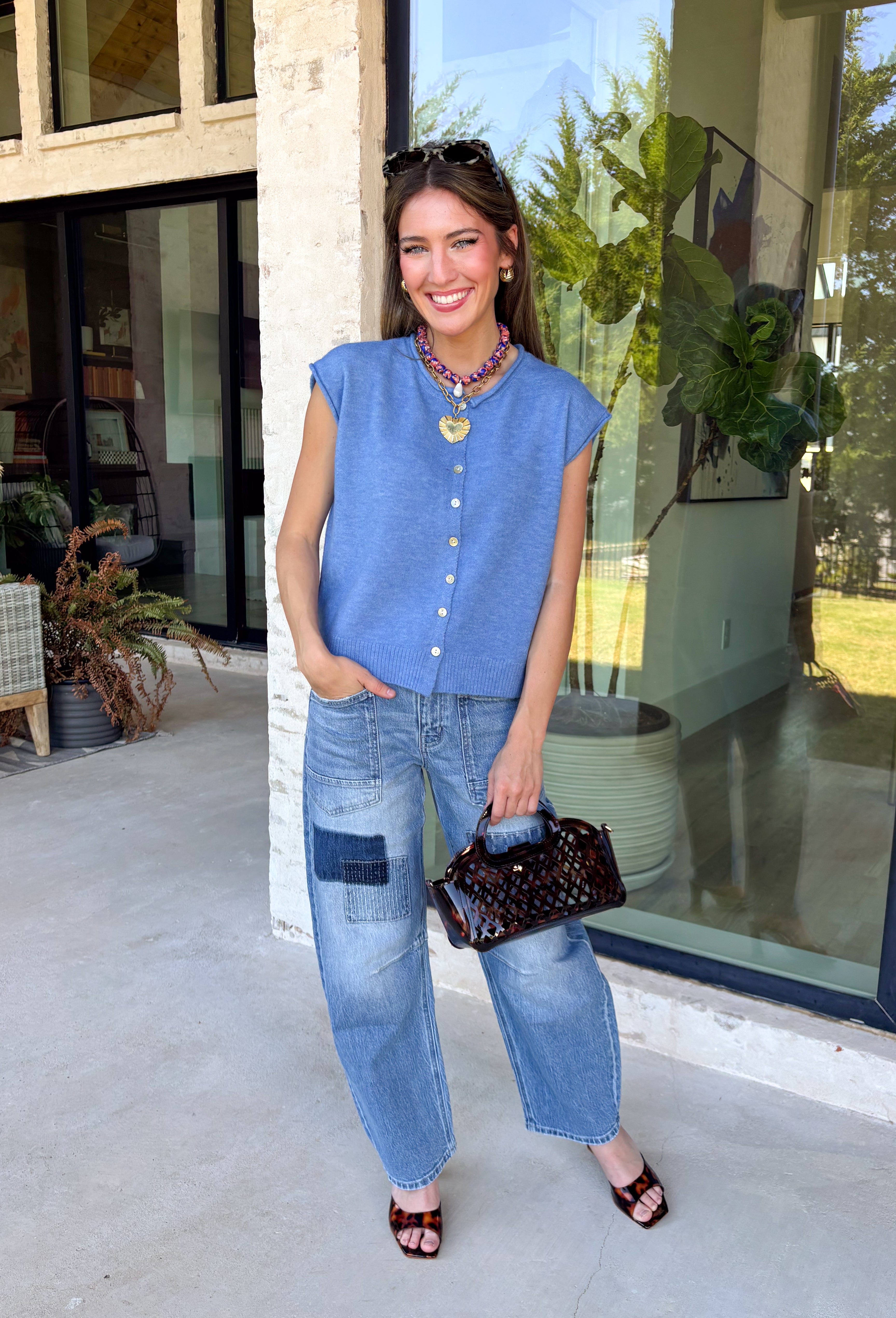 Layering season calls for pieces that can keep up with changing temperatures, and this blue sleeveless cardigan from Double Zero is ready for just that. The cozy knit brings plenty of texture and warmth, while the sleeveless design makes it easy to wear alone on milder days or layer over a long sleeve top as winter gets closer. A button-down front gives you multiple ways to style it, and the ribbed hem adds a classic sweater finish.