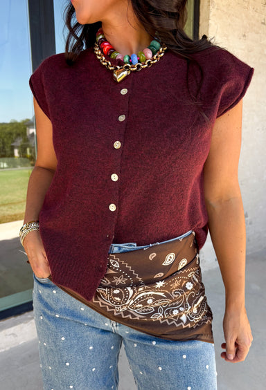 Layering season calls for pieces that can keep up with changing temperatures, and this dark cherry sleeveless cardigan from Double Zero is ready for just that. The cozy knit brings plenty of texture and warmth, while the sleeveless design makes it easy to wear alone on milder days or layer over a long sleeve top as winter gets closer. A button-down front gives you multiple ways to style it, and the ribbed hem adds a classic sweater finish. 