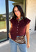 Layering season calls for pieces that can keep up with changing temperatures, and this dark cherry sleeveless cardigan from Double Zero is ready for just that. The cozy knit brings plenty of texture and warmth, while the sleeveless design makes it easy to wear alone on milder days or layer over a long sleeve top as winter gets closer. A button-down front gives you multiple ways to style it, and the ribbed hem adds a classic sweater finish. 