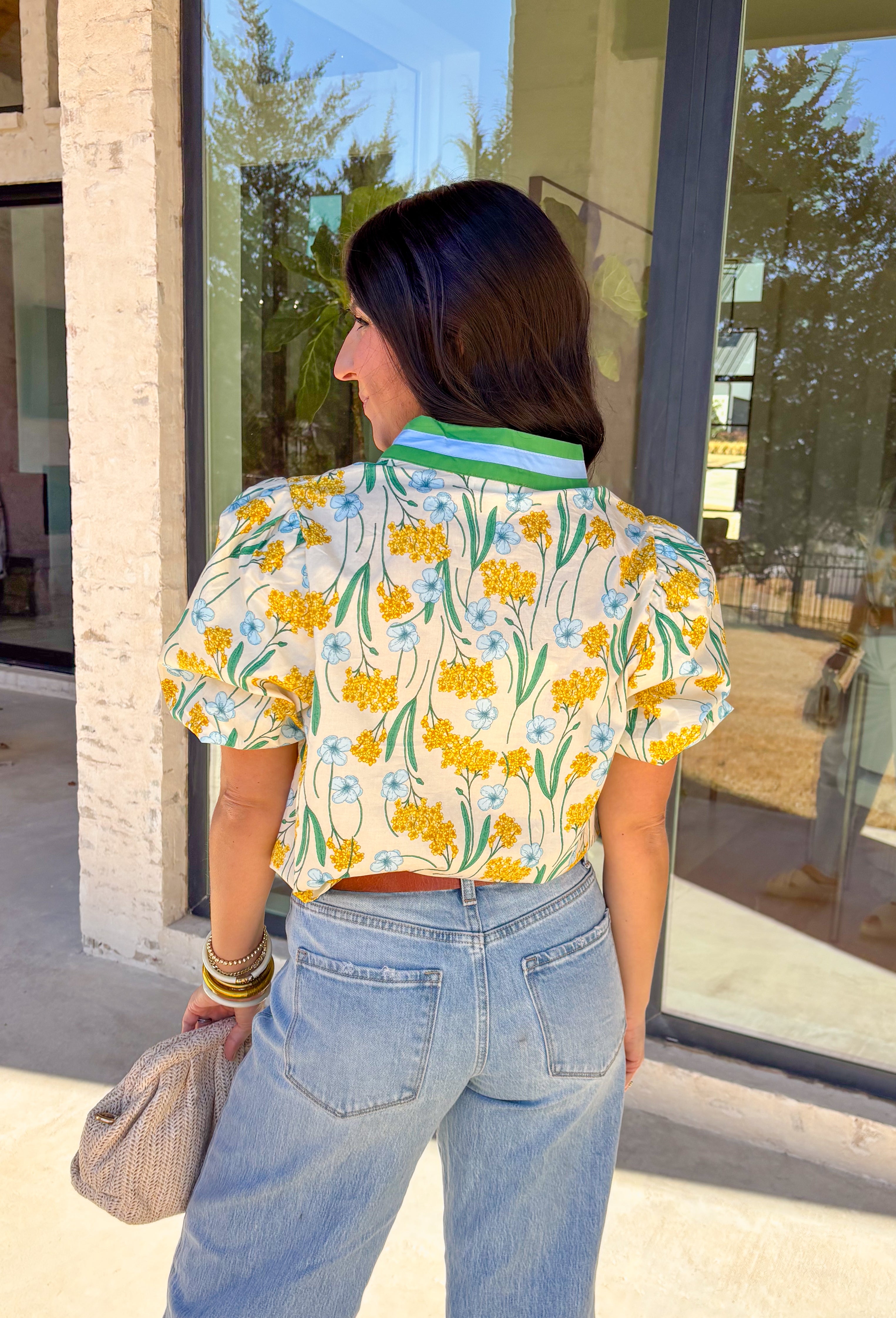 Bright, happy, and made for spring days, this cream short sleeve top by Entro is full of charming details. Featuring a colorful floral print with pops of yellow, blue, and green, it brings an easy burst of color to your look. The green and blue trim along the top adds contrast, while the blue scalloped trim gives it a sweet, polished finish. Puff sleeves complete the look with a soft, feminine touch, making this top perfect for sunny days ahead.
